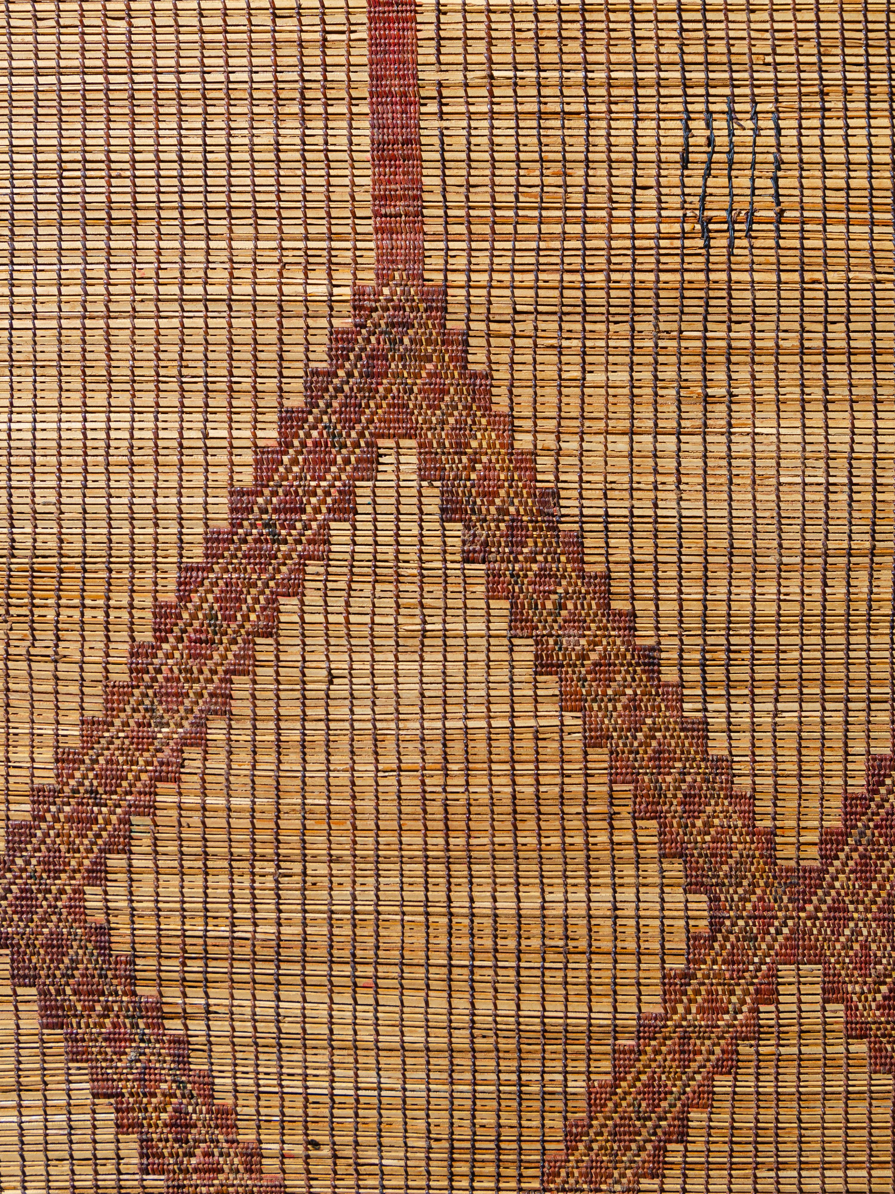 Woven by the nomadic Tuareg tribes of Mauritania with palm reed and leather, these mats offer a textural alternative to traditional woven textile floor coverings. This piece exhibits a rather symmetrical prominent lozenge pattern small diversions