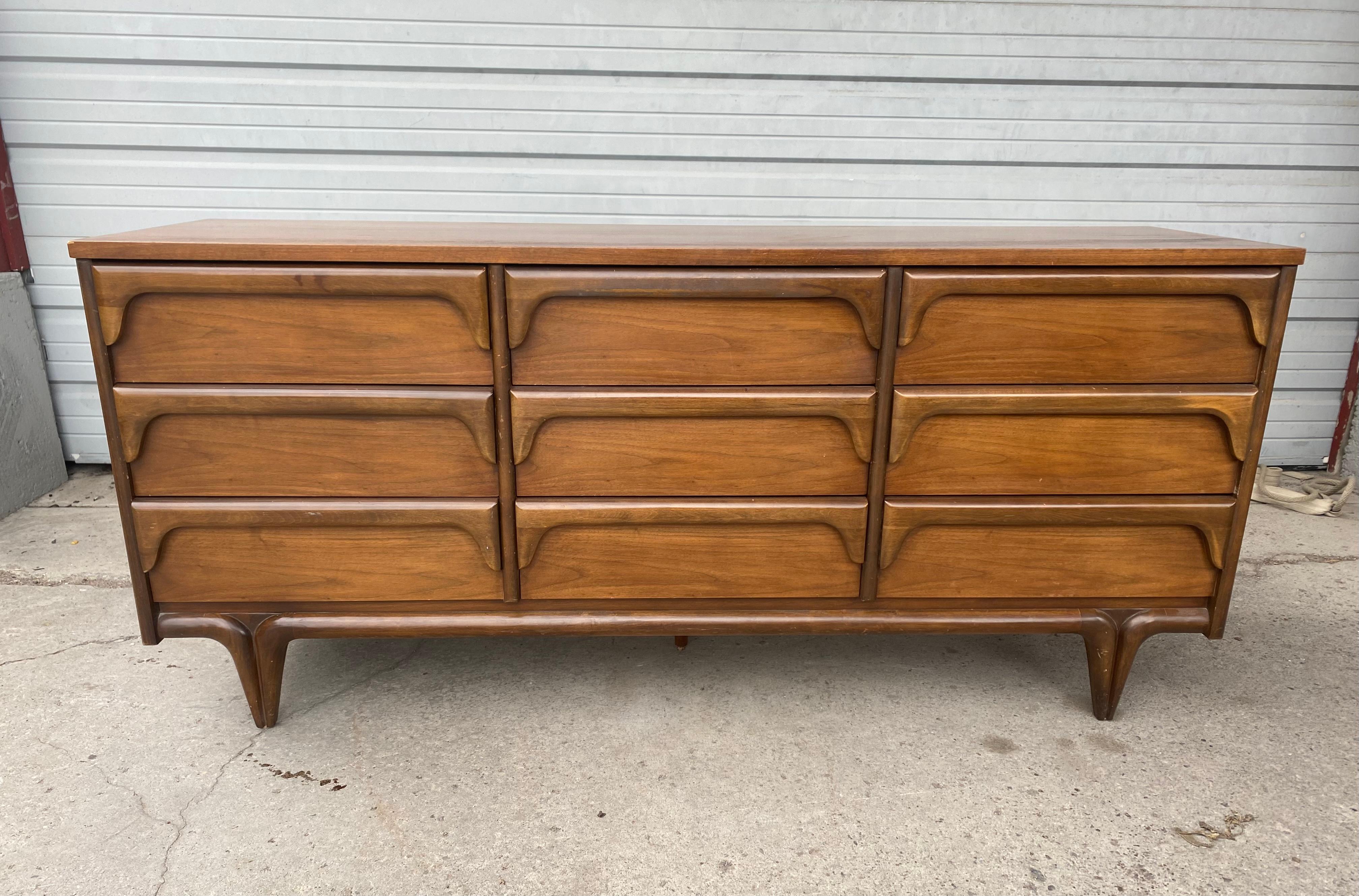 Classic Mid-Century Modern 9-drawer dresser, sculptural walnut by Bassett Furniture company. Wonderful design, Elegant yet whimsical, Superior quality and construction, dove-tail drawers. Generous storage, Smooth function, hand delivery avail to New