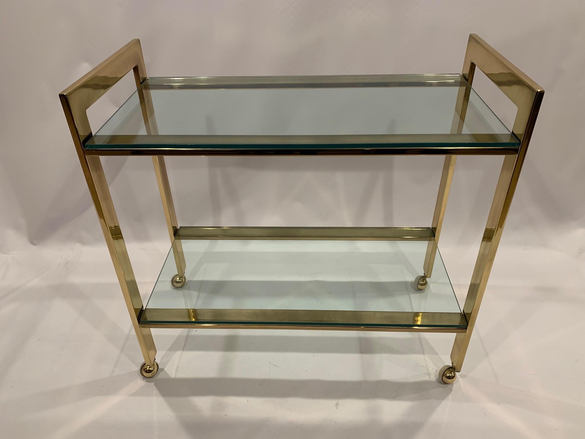 Classic Mid-Century Modern brass and glass Mastercraft bar cart having two tiers and smoothly functioning casters.