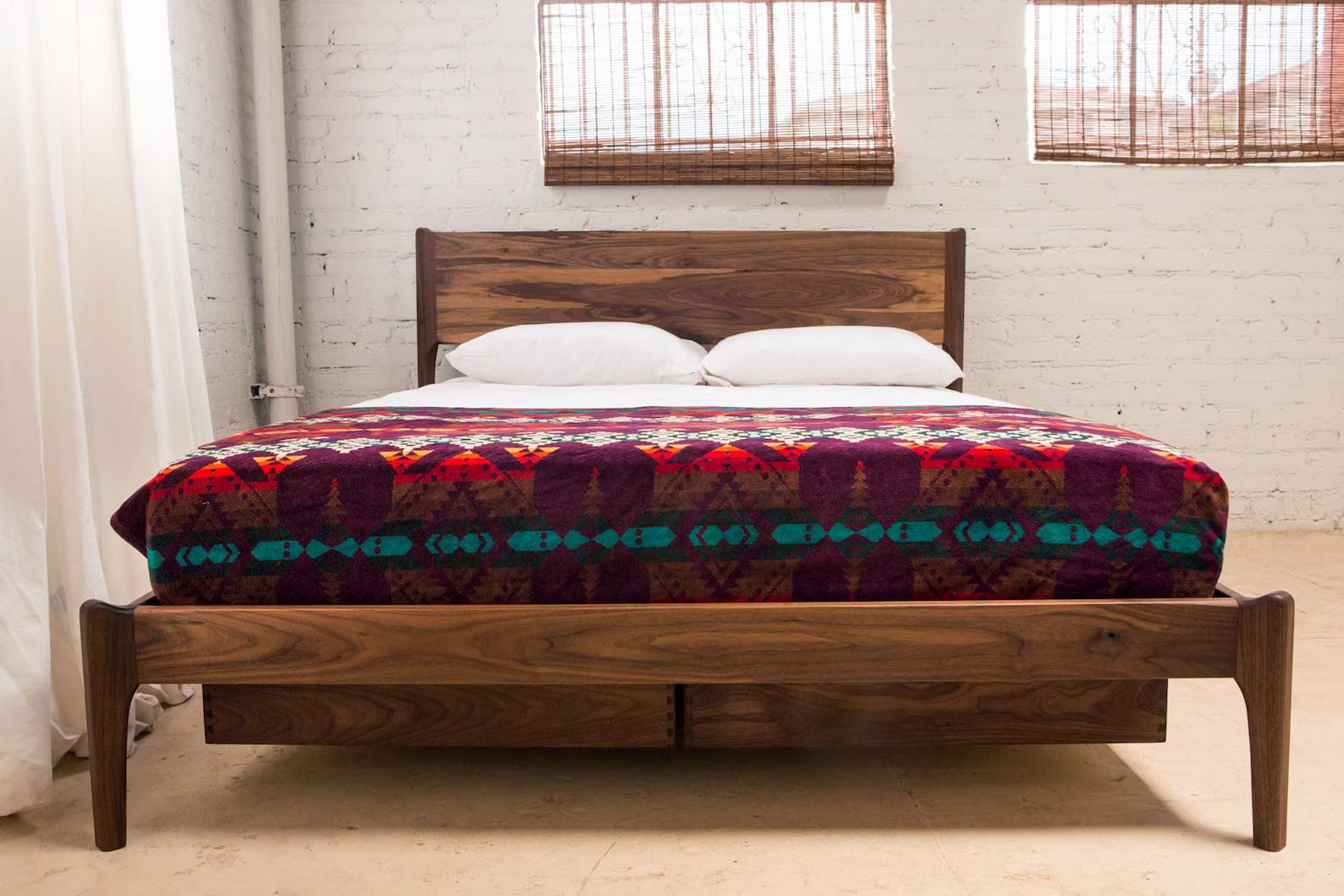 This bed is designed and hand-crafted by yours truly in Long Beach, Ca. The bed pictured is built from walnut, but I can use other woods upon request. The design is my own, inspired by a Mid Century/Danish modern aesthetic. All joinery is mortise