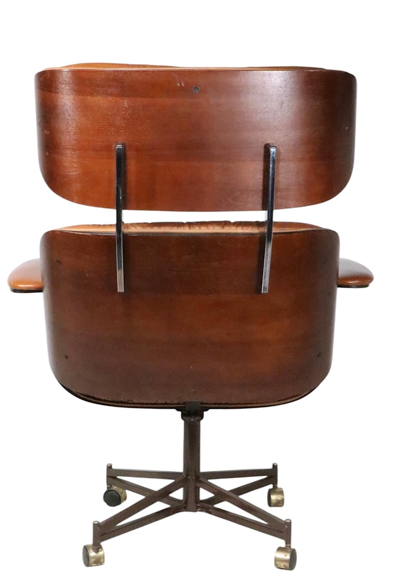 Iconic Plycraft Mr. style lounge chair and ottoman, executed in bent plywood,  vinyl faux leather, chrome and steel. The chair swivels and tilts on its center pole support, which is mounted on an architectural four metal star base. Included is the