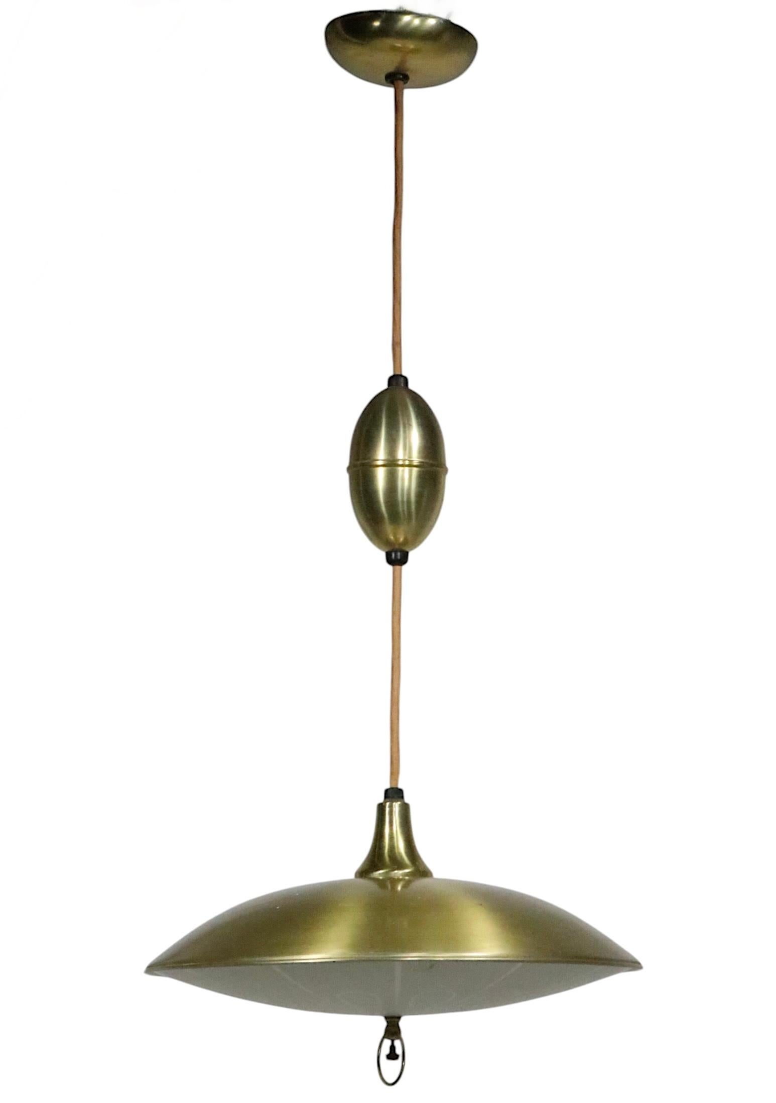    Lampadario classico a disco, a piattino, di metà secolo in  alluminio anodizzato, ottone e vetro. Il paralume a forma di disco presenta il suo diffusore originale in vetro e il paralume in metallo perforato. Il lampadario a disco è sospeso da un