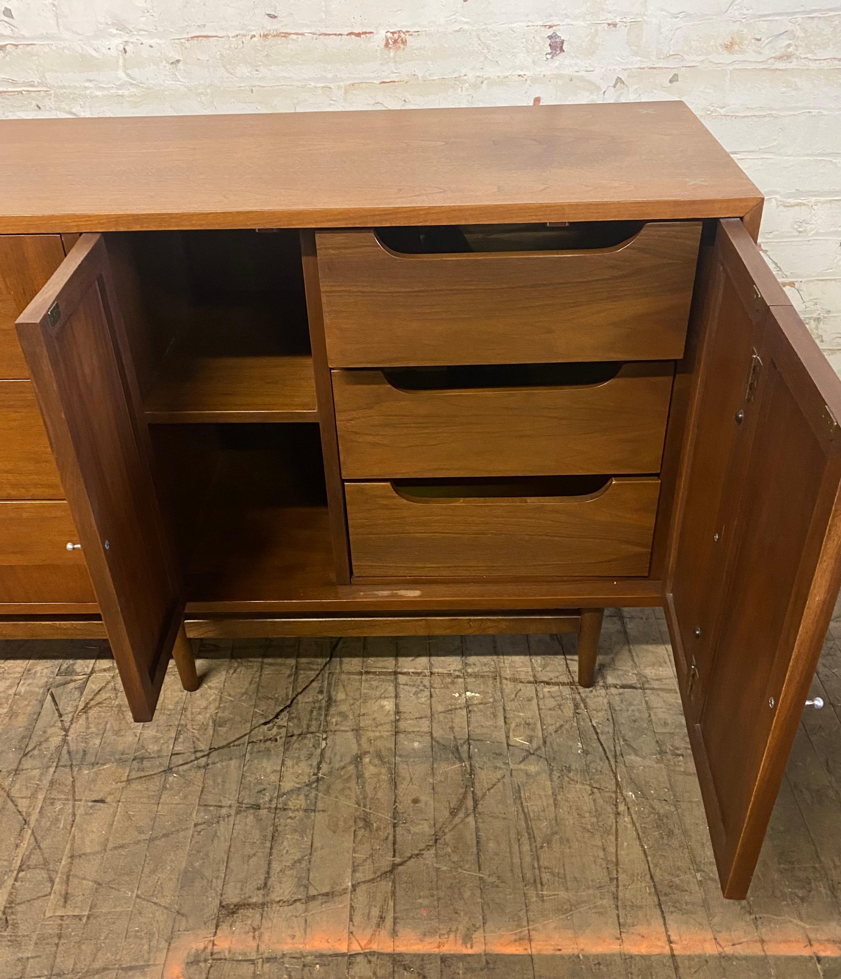 Stunning walnut modernist dresser designed by Merton Gershun, manufactured by American Of Martinsville. Classic aluminum x's and asymetrical pulls, minor stain to (see photo). Hand delivery avail to New York City or anywhere ken route from Buffalo