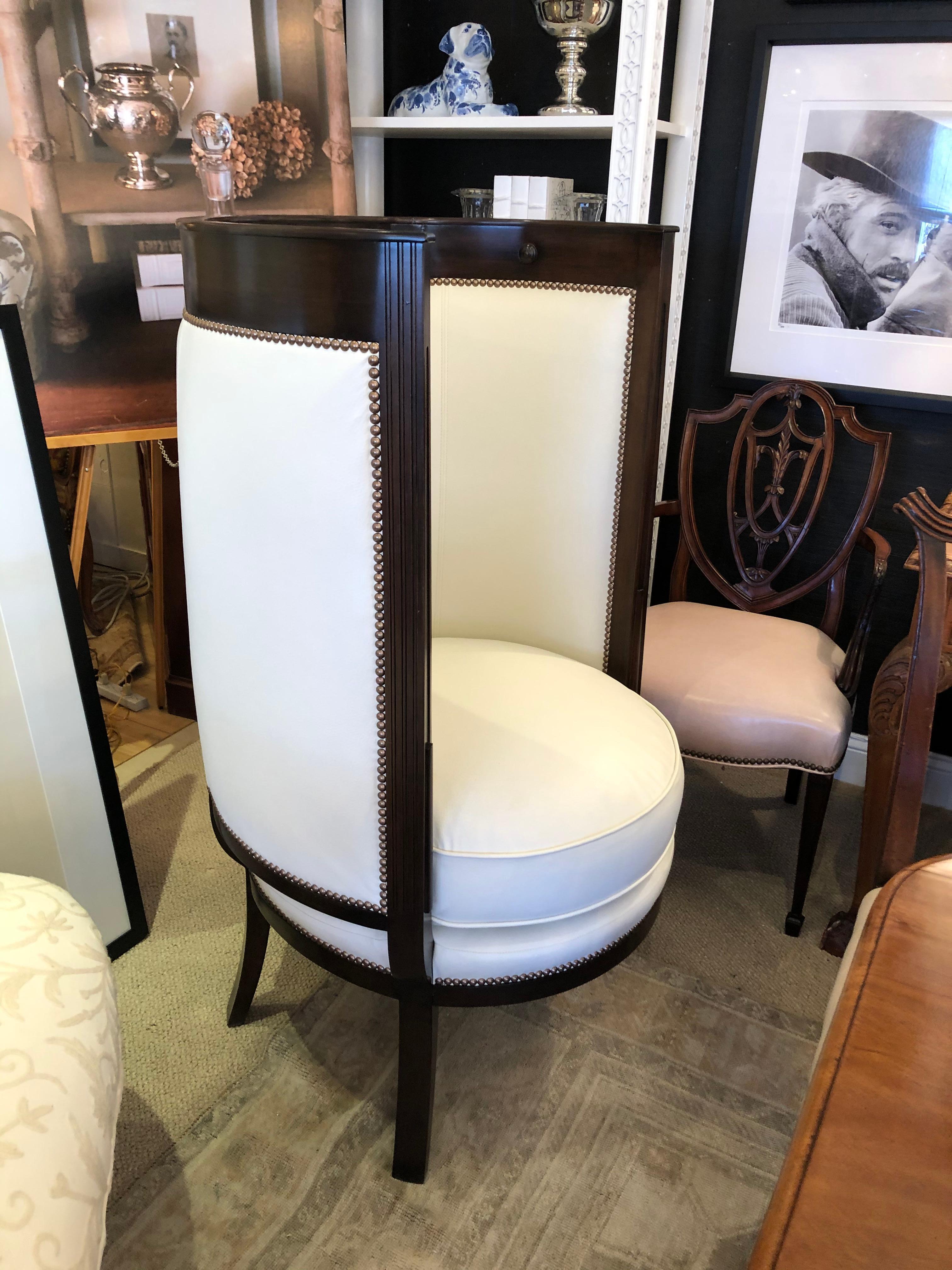 Classic and chic curvy hotel porter club chair having elegant dark walnut frame with medallion decoration and supple cream faux leather upholstery finished with nailheads. Custom design by high profile decorator, inspired by the romantic