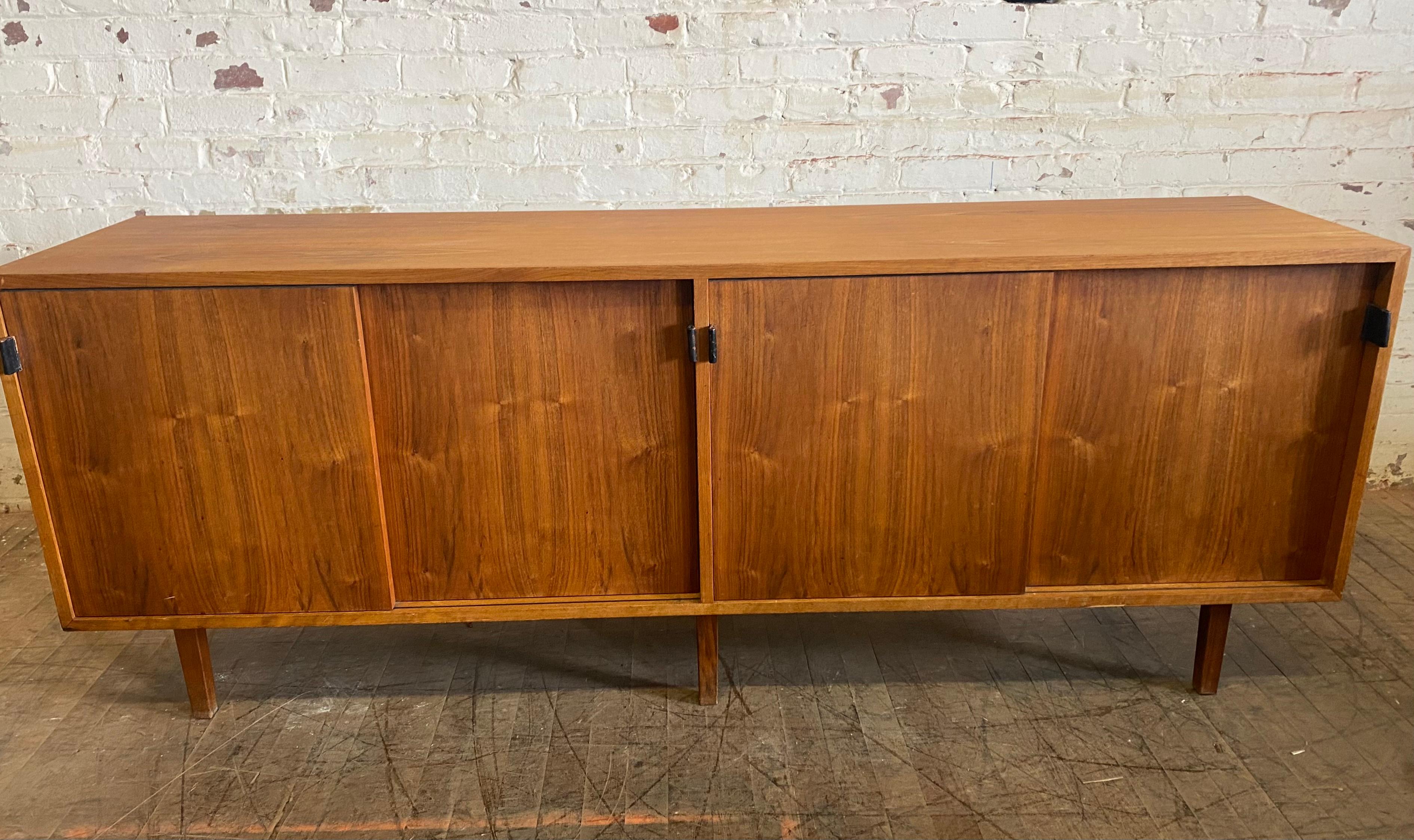 Classic modernist Florence Knoll walnut and oak Credenza with leather pulls and seldom seen wood legs.. Retains early Knoll label, Florence Knoll's simple. Elegant, understated design, 4 sliding doors , compartments with adjustable shelves, stunning