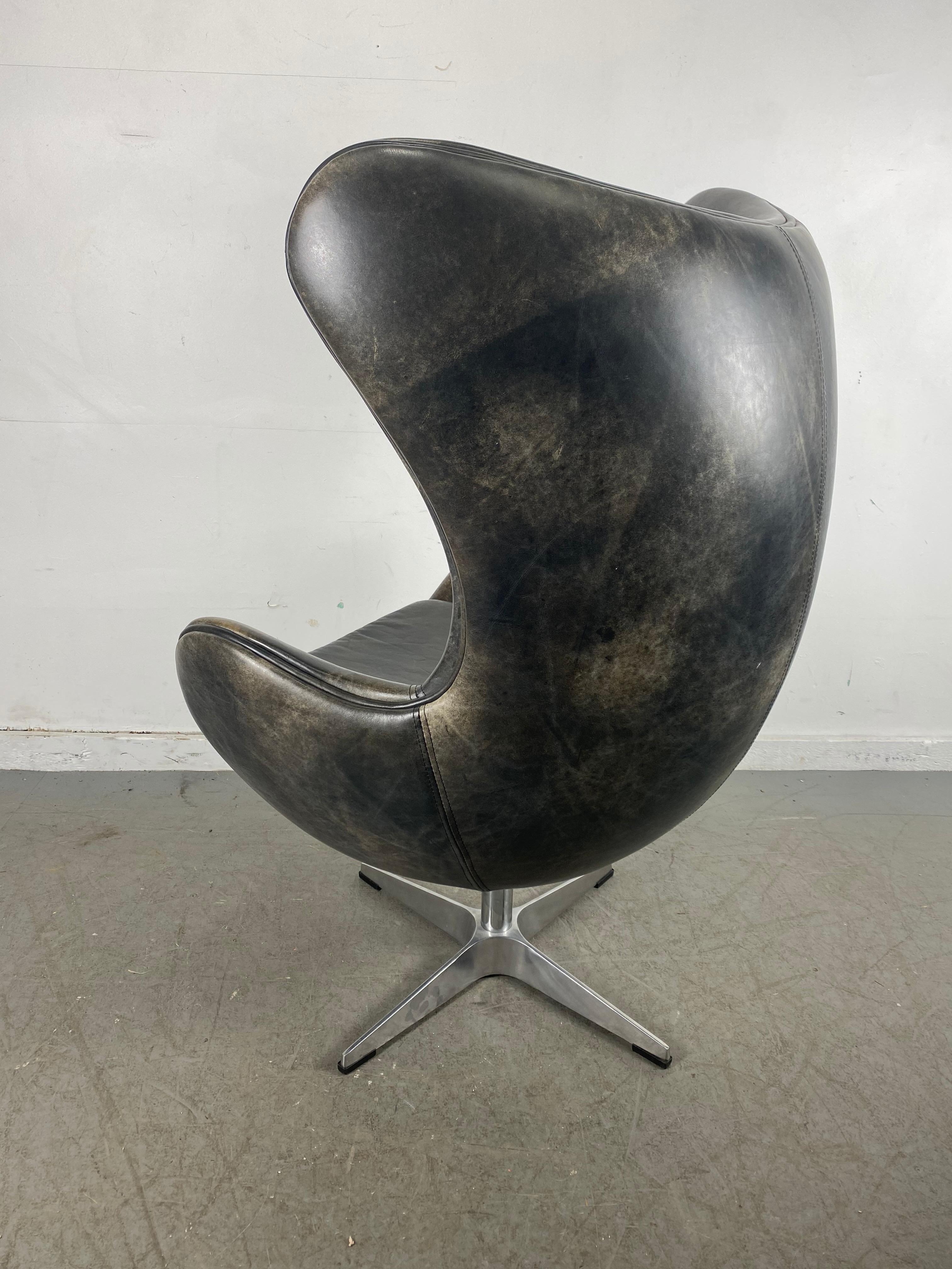 Classic modernist tilt/swivel egg chair in leather originally designed by Arne Jacobsen. c.1980s. Manufacturer unknown. Beautiful chair, modern icon! Nice original condition. Marbleized black/brown distressed leather upholstery. Really nice quality