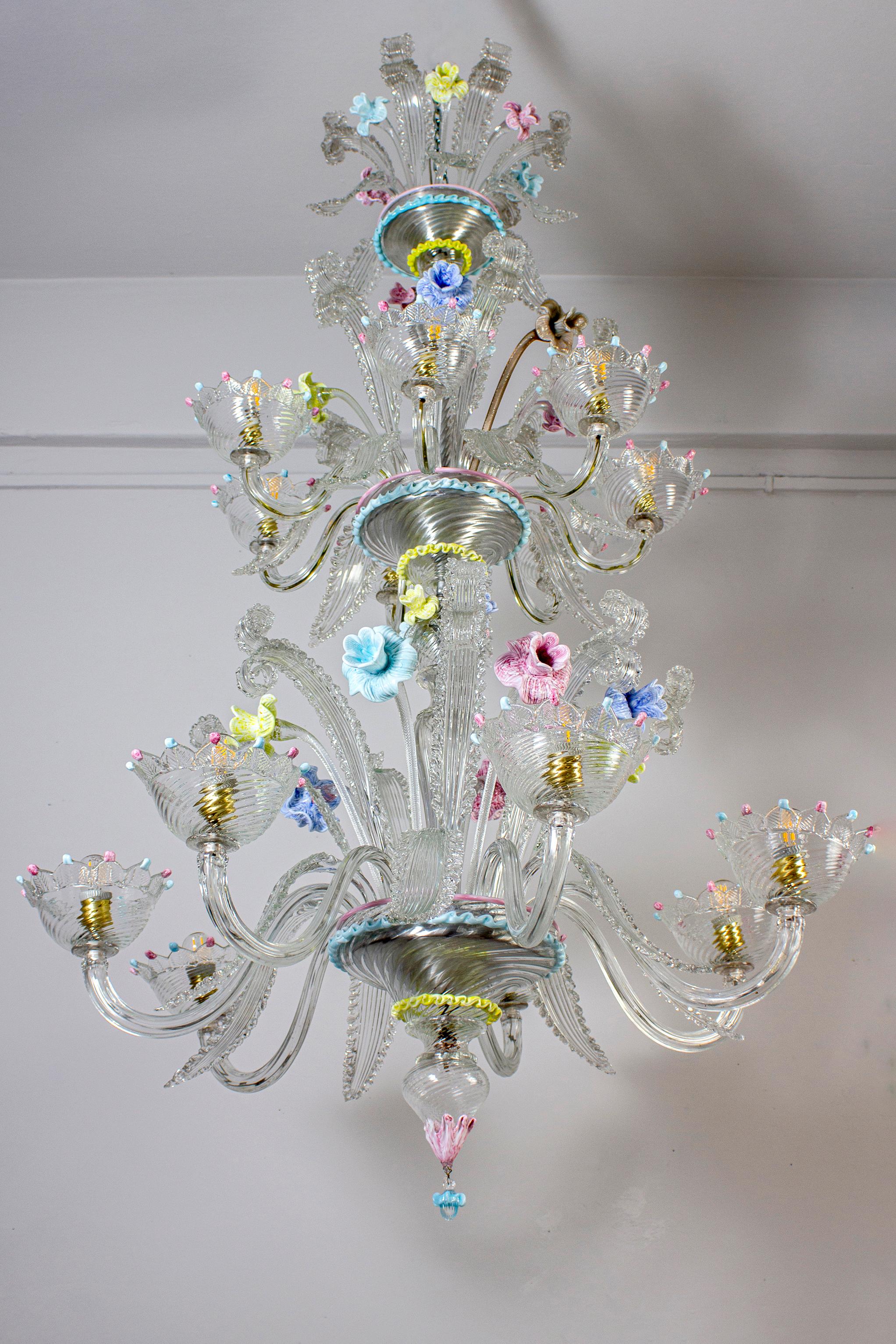 Spectaculaire lustre de Murano. Les bras 14 sont disposés sur deux étages. Les verres sont ornés de décorations colorées.  et des fleurs multicolores étonnantes. 
 14 ampoules avec 7 E27 et 7 E 14  ou nous pouvons câbler tous les  avec E 14