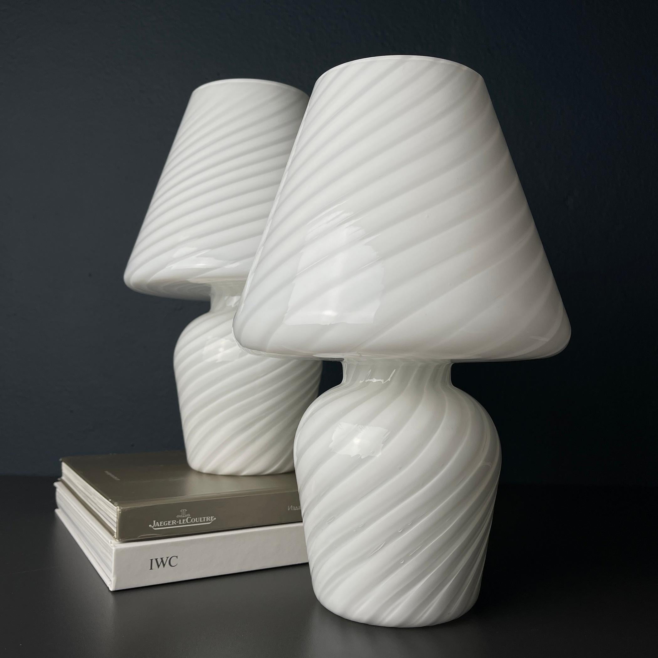 Step into a realm where art and illumination dance in harmony with this captivating pair of Murano mushroom lamps, born in the creative fires of 1970s Italy. An ode to the timeless allure of Murano glass, these lamps are not mere fixtures; they are