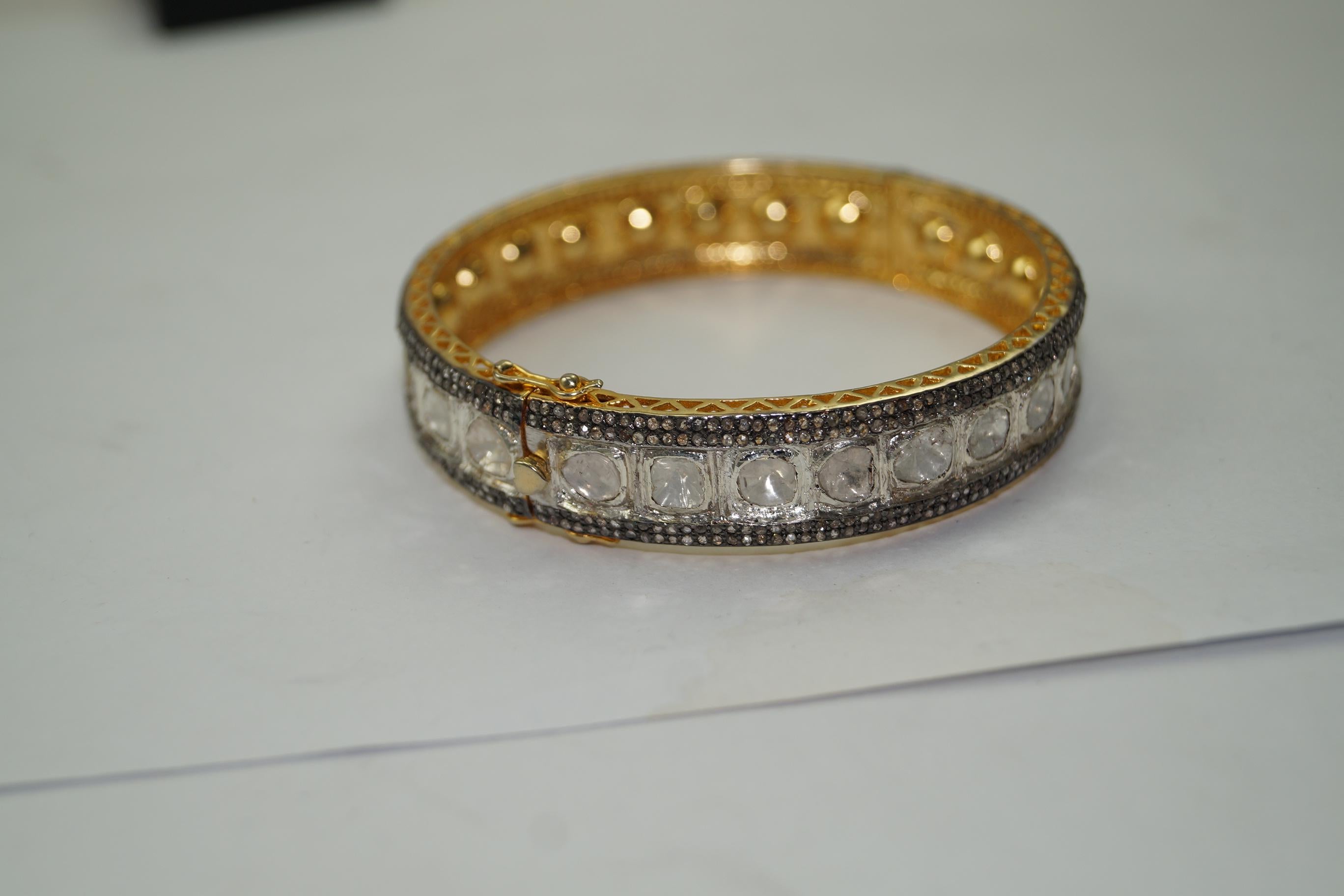 This vintage style diamond silver and yellow gold plating hinged bangle consists of:

Diamond- 7.30cts
Diamond type: Rose cut diamonds and uncut polki diamond
Diamond color:  white and tinted yellow
Diamond origin- Natural
Metal: Silver
Metal