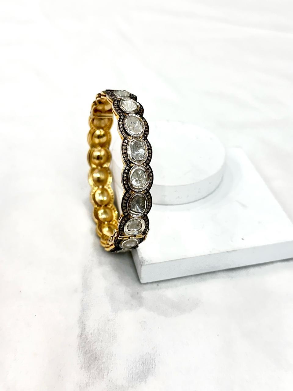 This vintage style diamond silver and yellow gold plating hinged bangle consists of:

Diamond- 7.50cts
Diamond type: Rose cut diamonds and uncut polki diamond
Diamond color:  white and tinted yellow
Diamond origin- Natural
Metal: Silver
Metal