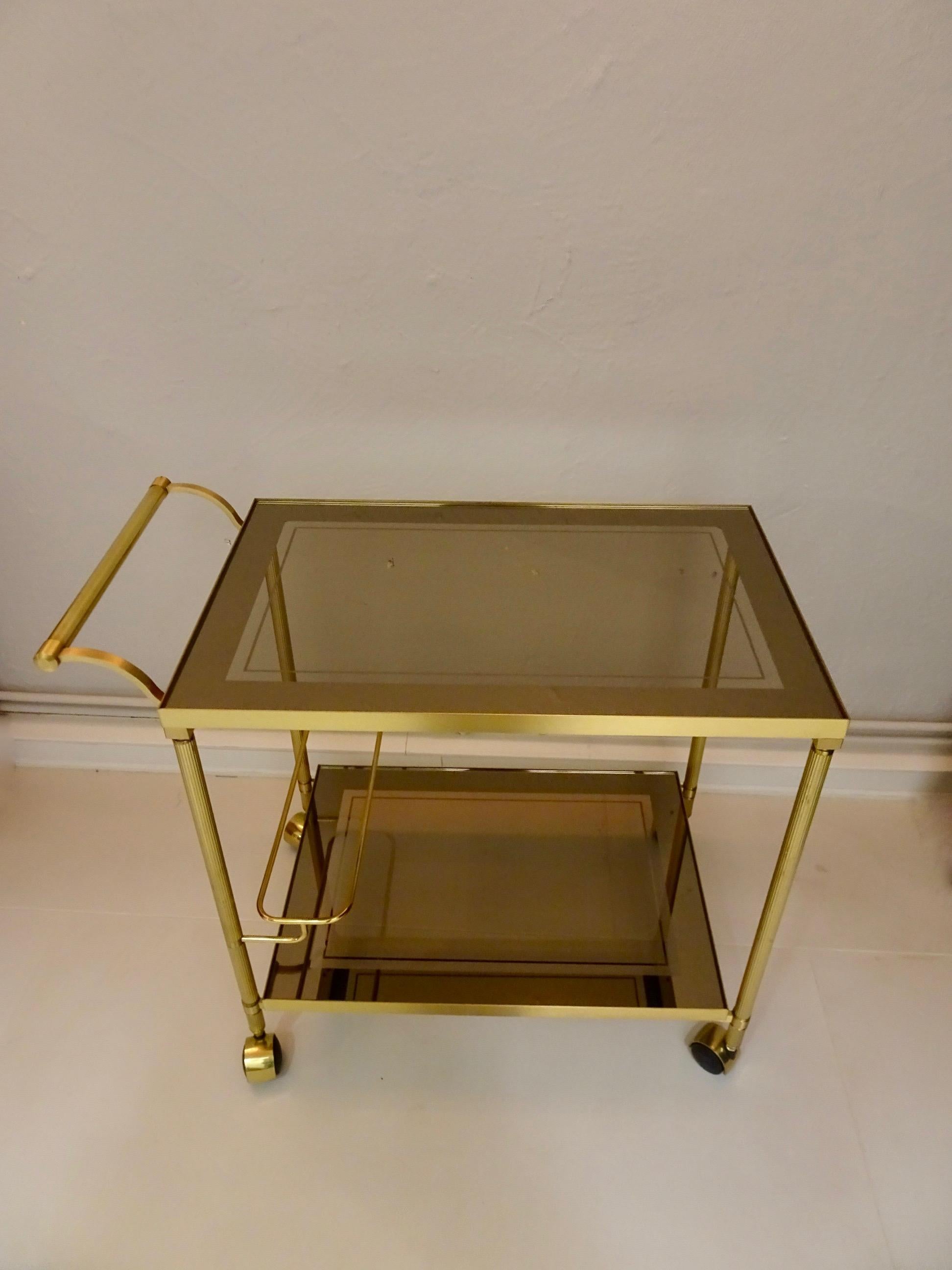 Classic neoclassical / Hollywood Regency gilded brass trolley. Dark tinted glass top.

Dimensions: 66.5 x 67.5 x 43 H cm

Condition: Very good condition, normal wear visible in picture.
  