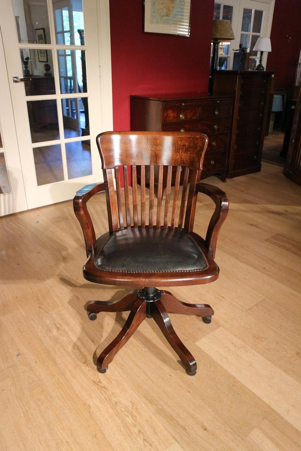 Classic office chair in mahogany version with black leather seat. Chair has parquet wheels and is height adjustable. Also equipped with adjustable rocking mechanism. In very good condition.