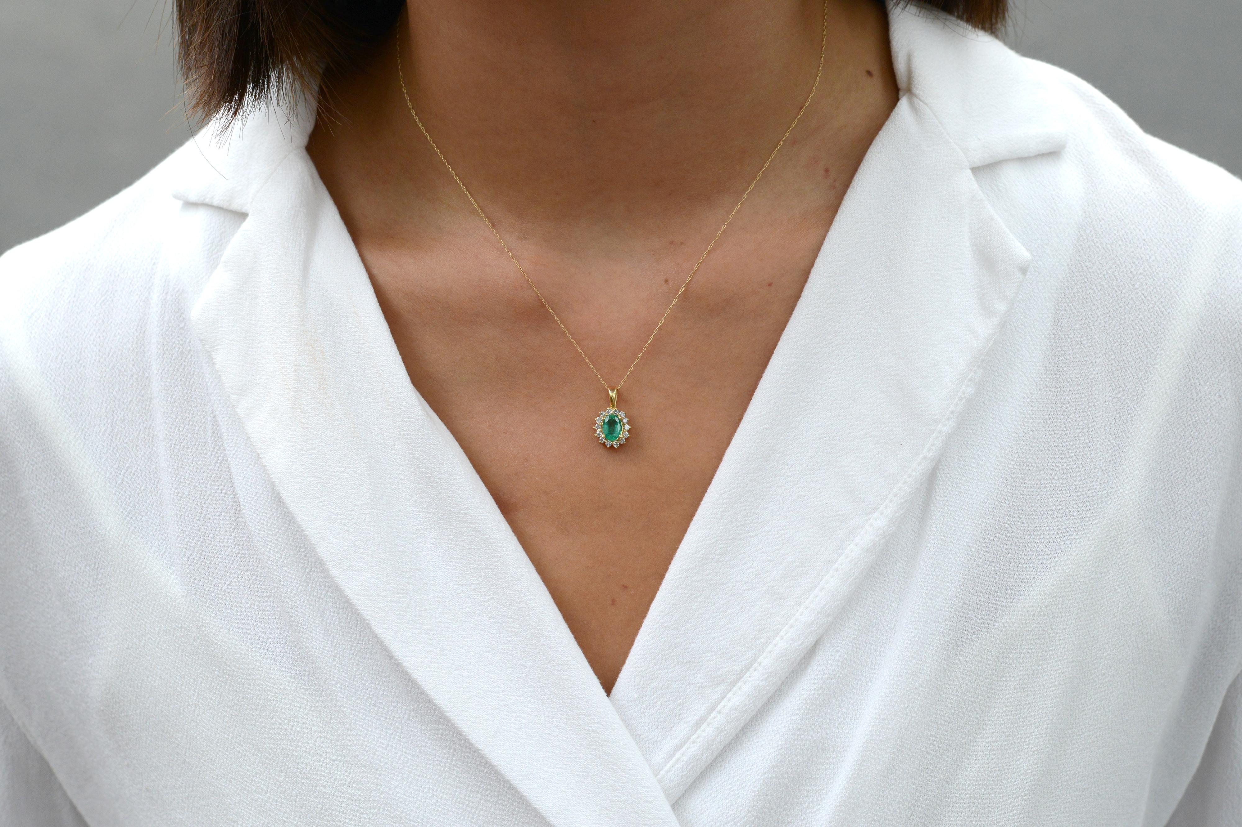 An affordable contemporary expression, this luxurious necklace is crafted with a lush, light green natural emerald, 14 karat yellow gold and a halo of sparkly and clear diamonds. The stunning pendant style necklace presents a delicate complexity