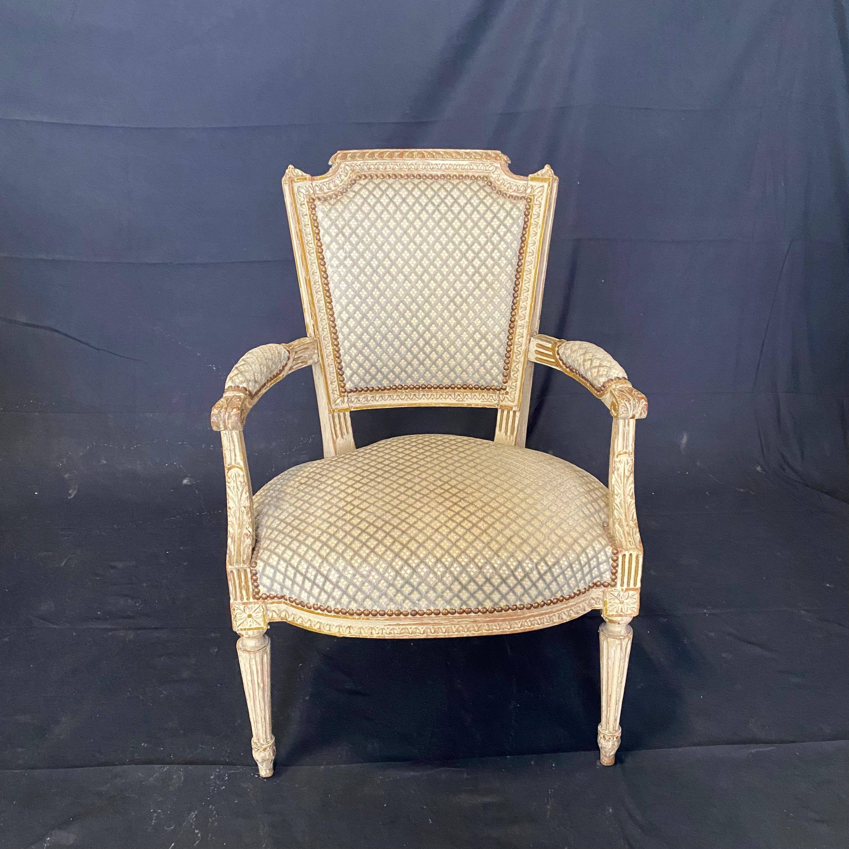 Elegant French Louis XVI period chairs with original white and gold paint. Classic diamond pattern fabric accented on all sides with nailhead trim. 
Measure: Arm height 24.5
Seat height 17.5.

 