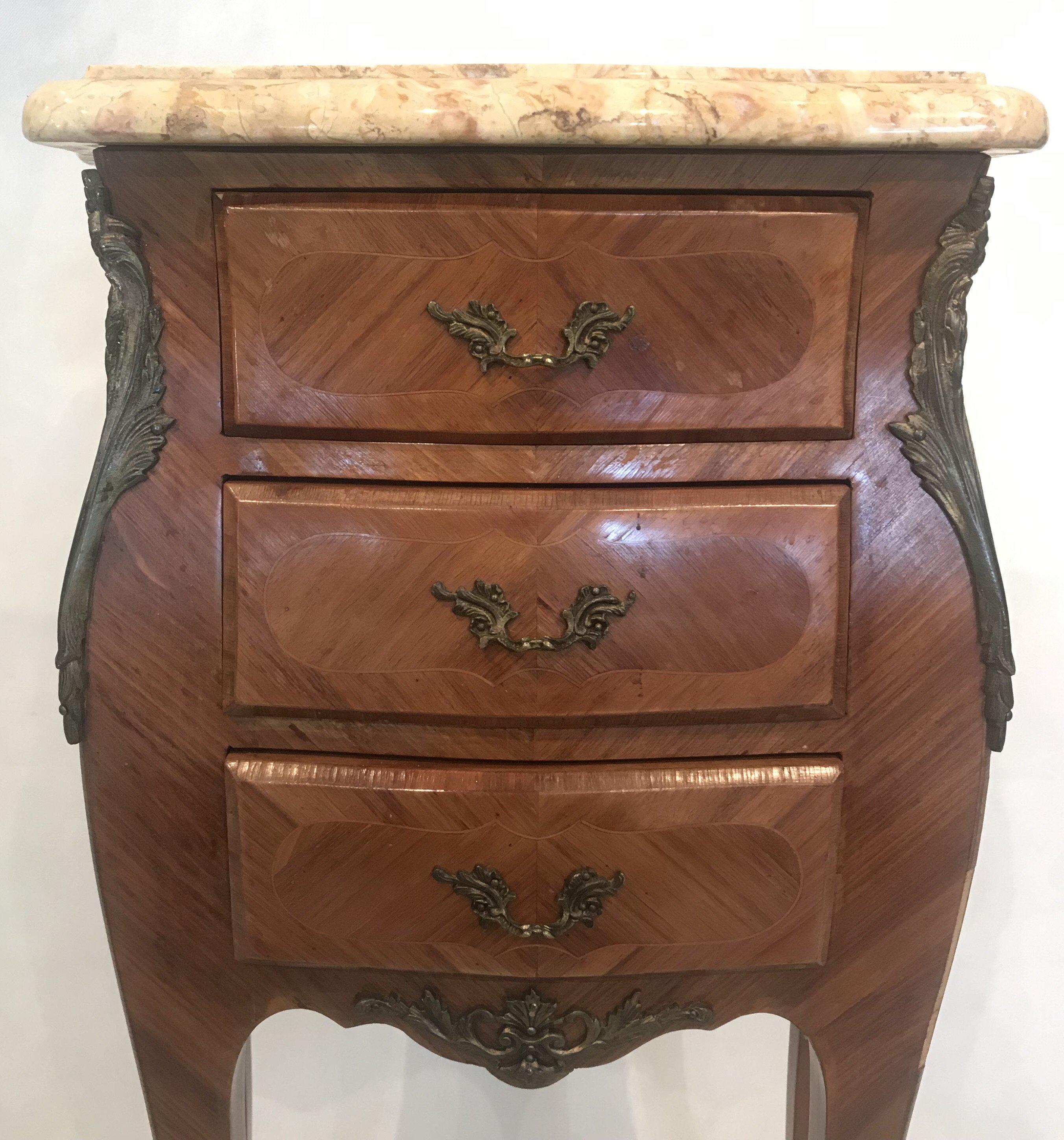 Pair of French Louis XV style beige marble top night stands having beautifully shaped marble top with molded edge, over case with herringbone inlay, gilt metal mounts, three drawers, and elegant legs with French bracket feet. Some minor veneer