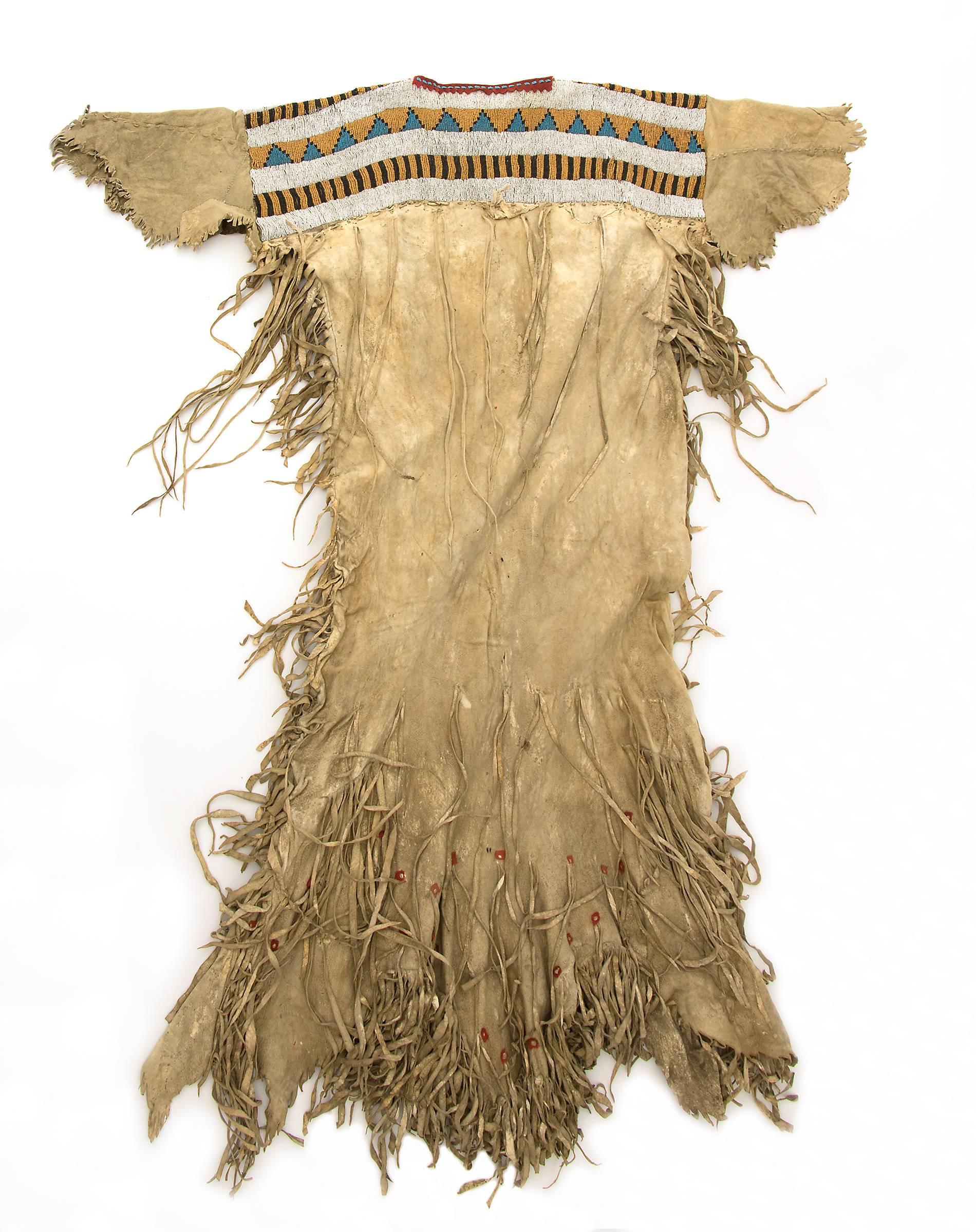 A Blackfeet (Northern Plains American Indian) beaded dress from the classic period (Pre-Reservation era). Constructed of Native tanned hide Pony beads, Real beads and Seed beads with red Cochineal-Lac dyed trade cloth. The Blackfeet/Blackfoot tribe,