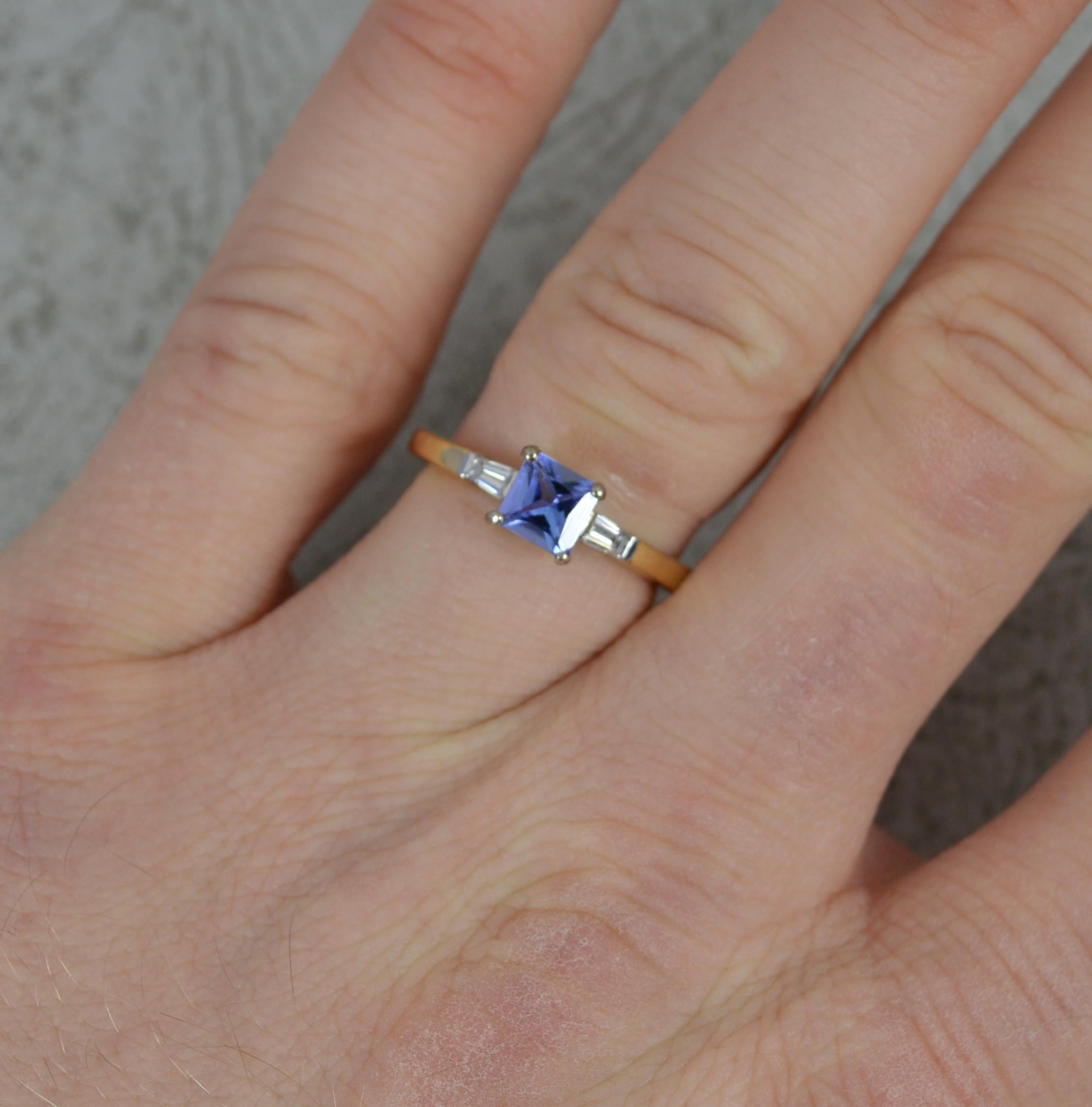 A stunning Tanzanite and Diamond ring.
​Solid 18 carat yellow gold shank and white gold head setting.
Designed with a princess cut tanzanite to centre. 5mm diameter. To each side are tapered baguette cut diamonds to each side.
11mm spread of stones.