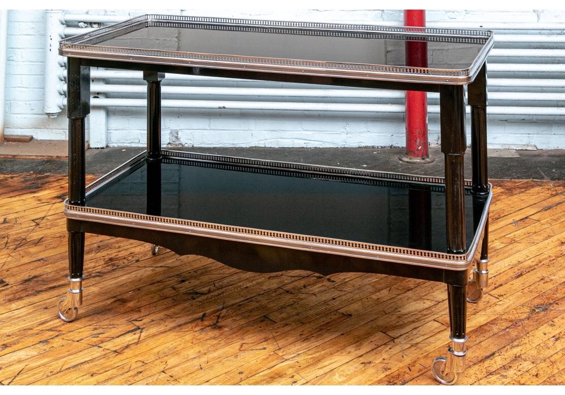 Classic Ralph Lauren design of a rectangular serving cart with black lacquered tiers and chrome openwork galleries. The lower tier with a shaped apron on all sides. Raised on fluted columnar legs mounted on chrome casters.
Measures: Length 47