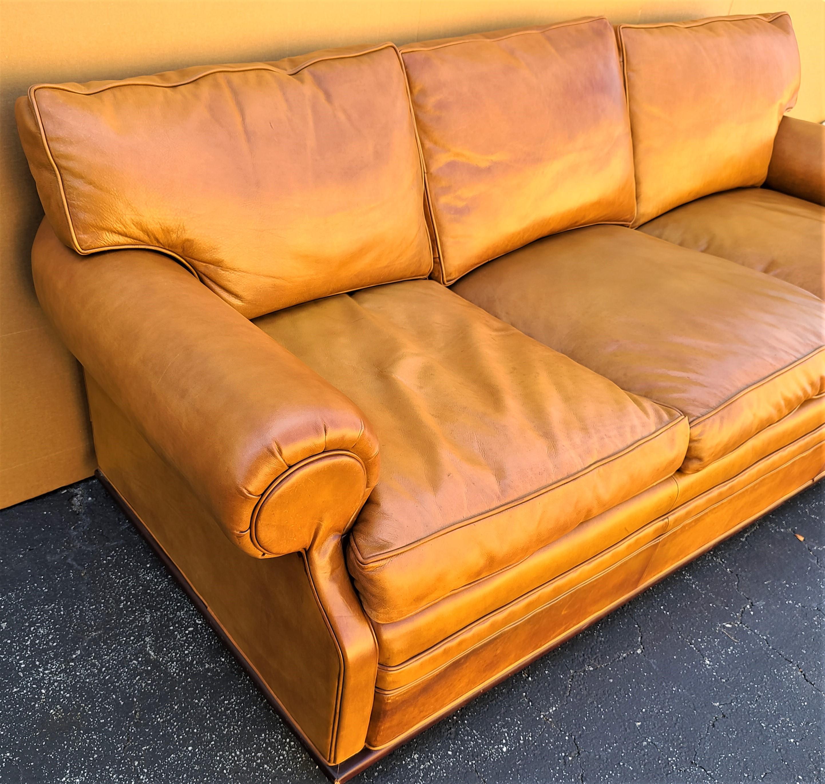 Offering one of our recent Palm Beach Estate fine furniture acquisitions of a
Gorgeous vintage Ralph Lauren caramel brown leather sofa with a classic roll arm shape and raised wood base with round feet. 
The wood base goes around the entire