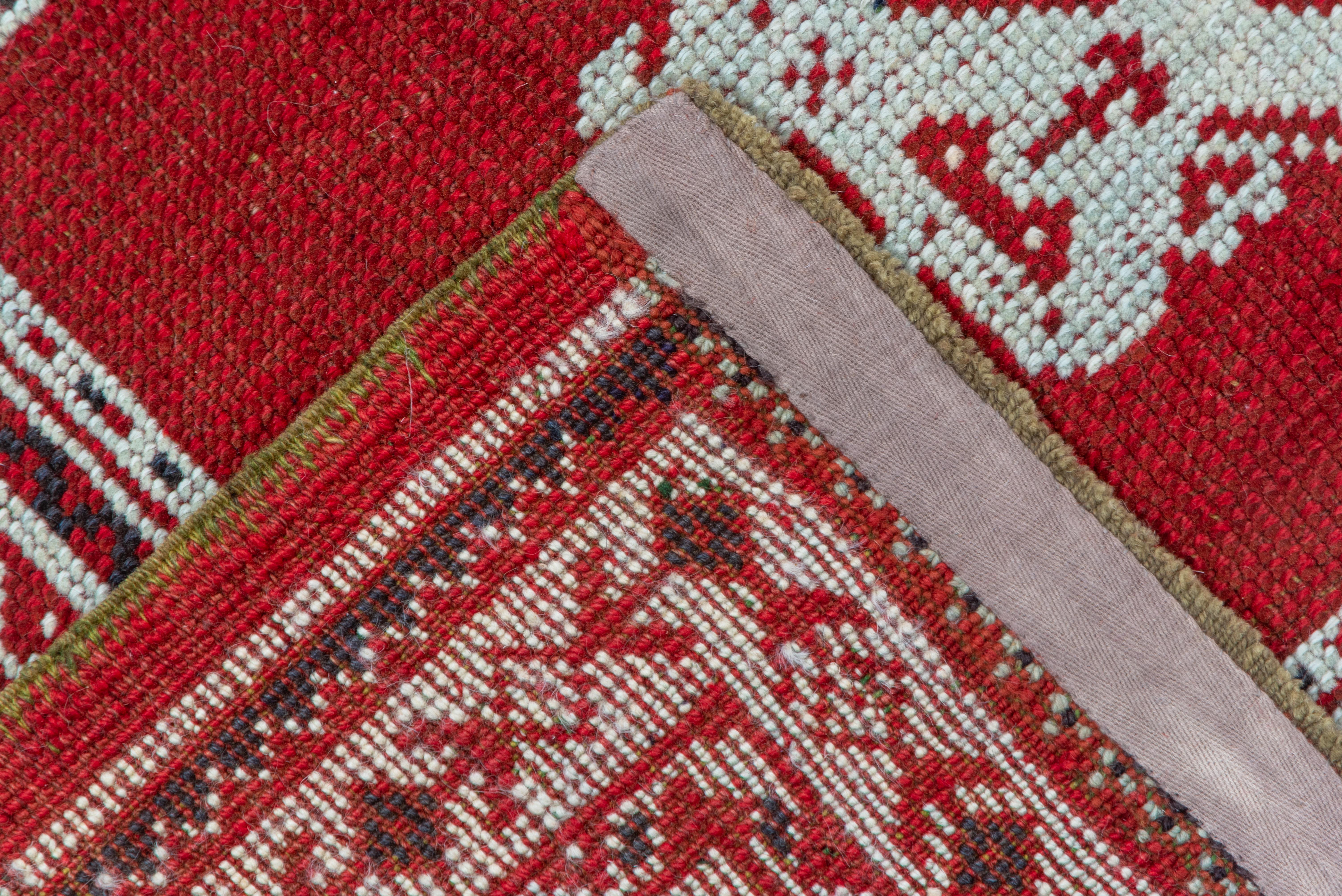 This 'Turkey Red' west Anatolian town carpet has a Yaprak and palmette pattern derived from 18th century archetypes. The red hyacinth and octagon rosette border also has earlier sources. Aqua blue and ivory are among the detail tones.