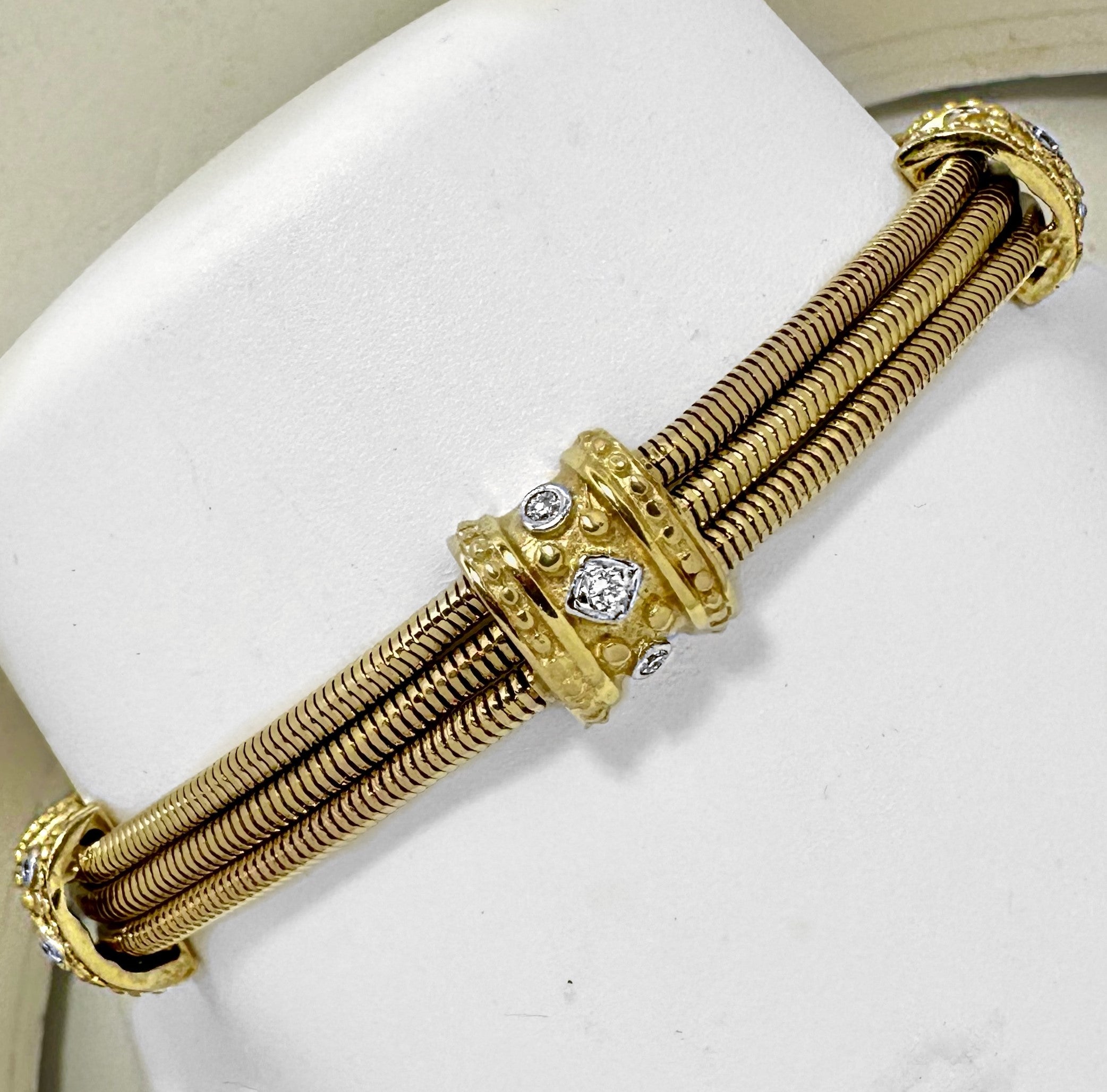 This very high quality Classic Revival style 14K yellow tri-strand snake chain bracelet is punctuated with five stations, each bezel set with three brilliant cut diamonds. Every station is finished in great detail with beaded edges and motifs