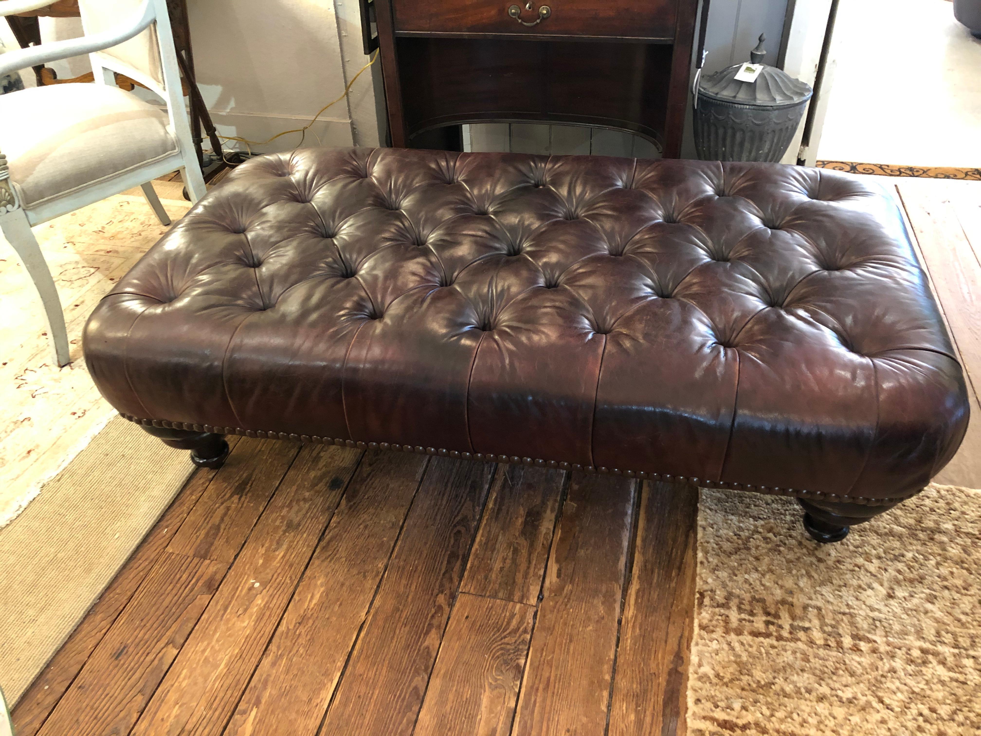 Classic rich George Smith tobacco tufted leather ottoman in the chesterfield style having mahogany bun feet and brass nailheads around the base. Label underneath. Newly oiled and waxed and to its utmost luxuriousness!