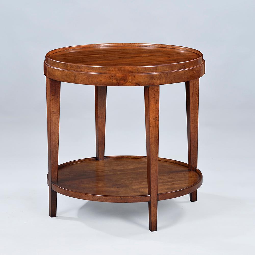 Une table d'appoint ronde de style classique avec une finition rustique et chaude teintée de noyer. Cette table d'appoint à deux niveaux présente un plateau en bois à galons, des pieds carrés effilés et une base ronde en forme