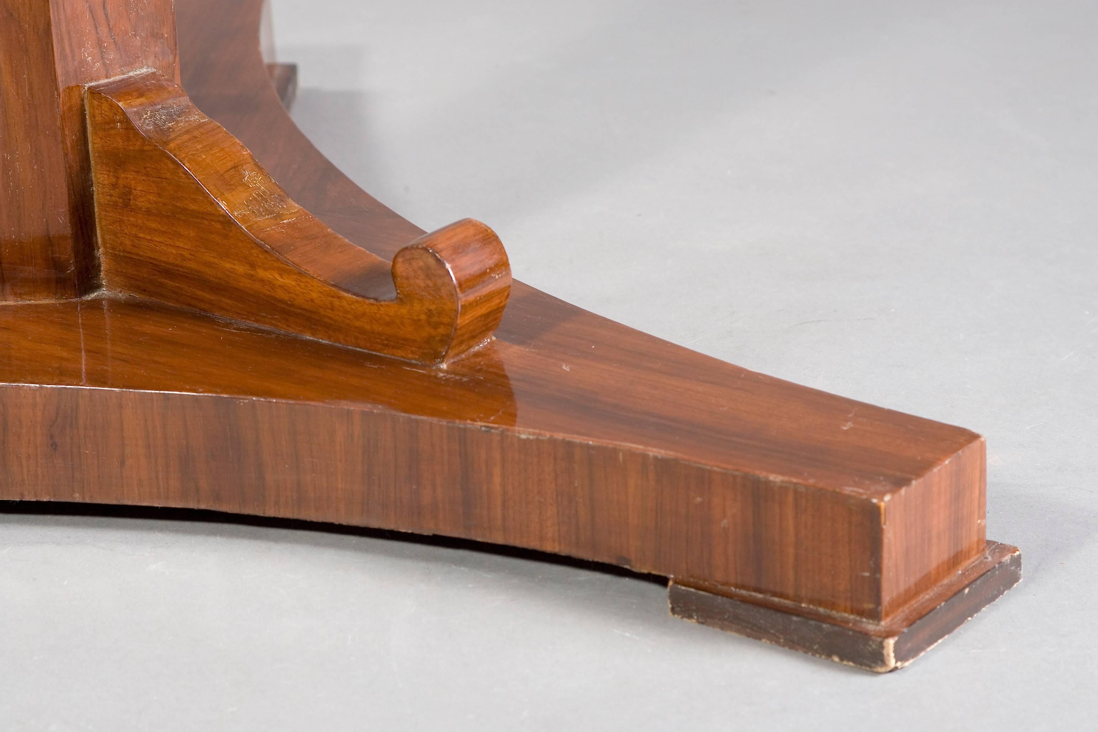 Mahogany on solid wood. Three-sided base plate on glass panes. Centrally ascending, eightfold folded column, flanked by three curved volutes. A strict form of early-Biedermeier time. It is equipped with a folding mechanism. This type is very