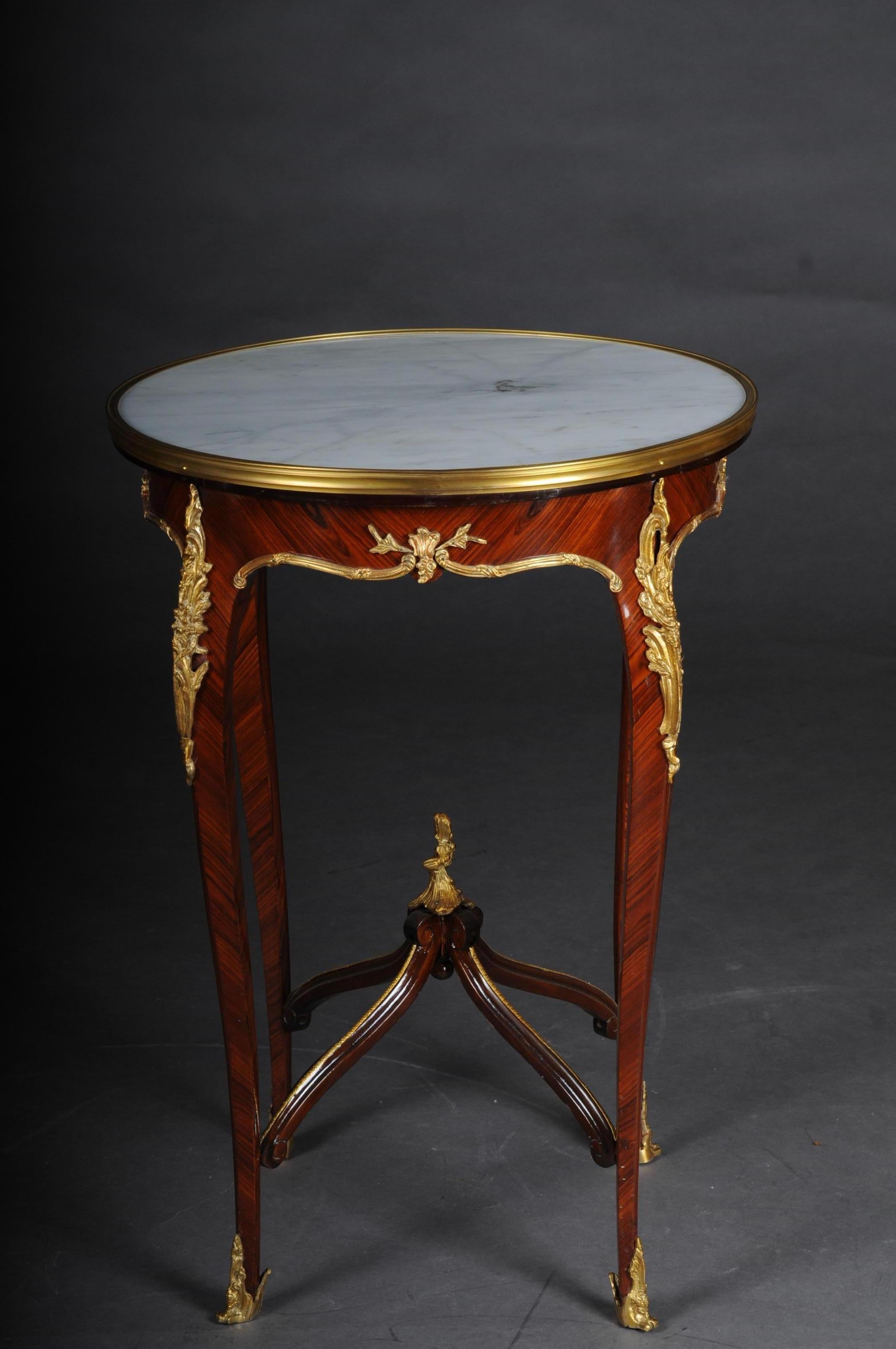 Classic saloon side table in the Louis XV after F. Linke.

Veneer on solid beech, daintily finished, body, flanked by solid corner strips on high, elegantly curved legs with bronze fittings ending in sabots. Slightly protruding, round marble top