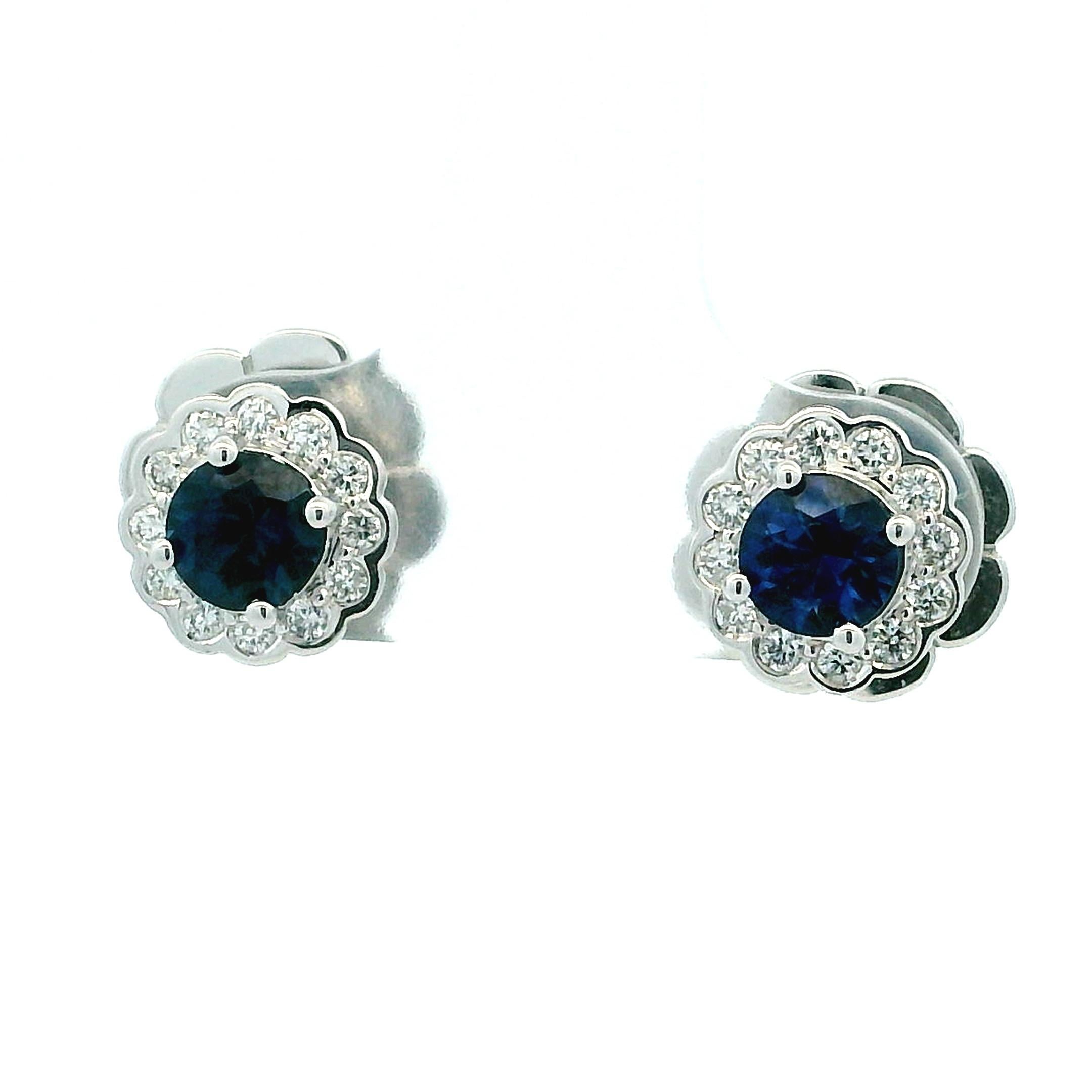 Une paire intemporelle et élégante de boucles d'oreilles à grappes de saphirs et de diamants en or blanc 14K. Chaque boucle d'oreille est ornée d'un saphir bleu royal rond au centre, encadré d'un halo de diamants brillants bien assortis, disposés