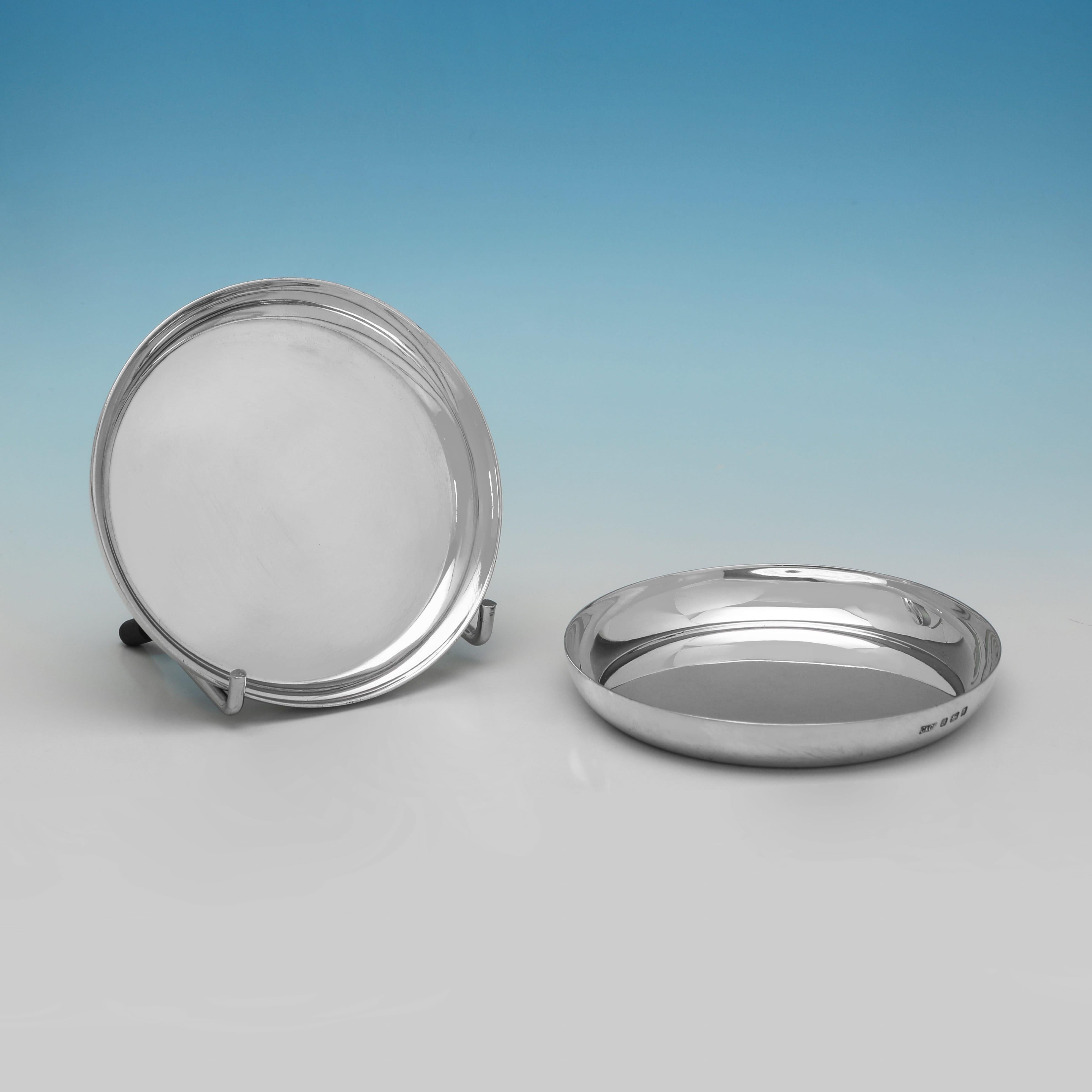 Hallmarked in London in 1937 by Carrington 
Co. this classic George VI sterling silver set of 12 wine glass coasters is of a plain, circular form with a polished surface and a shallow, raised rim. The coasters each measure 0.5