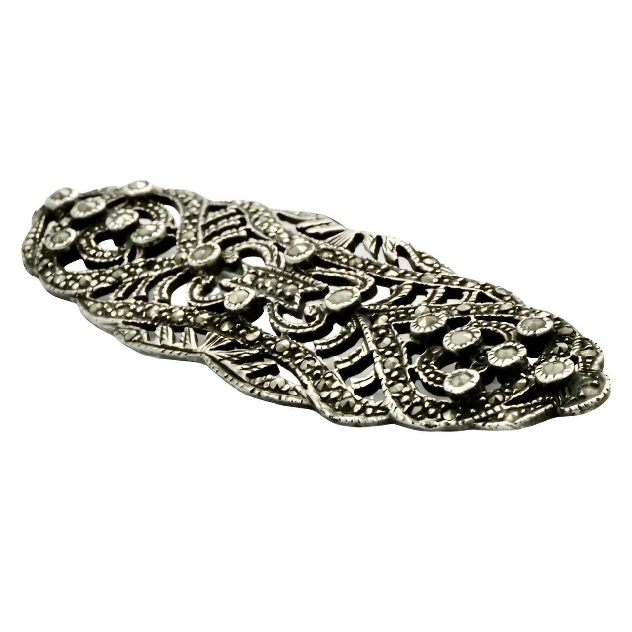 Beautiful classic silver brooch set with marcasites. Measuring length 7.6 cm / 3 inches by width 2.4 cm / .9 inch. We have given the brooch a light clean. We replaced two missing marcasites.

This is an ornate silver brooch with twinkling