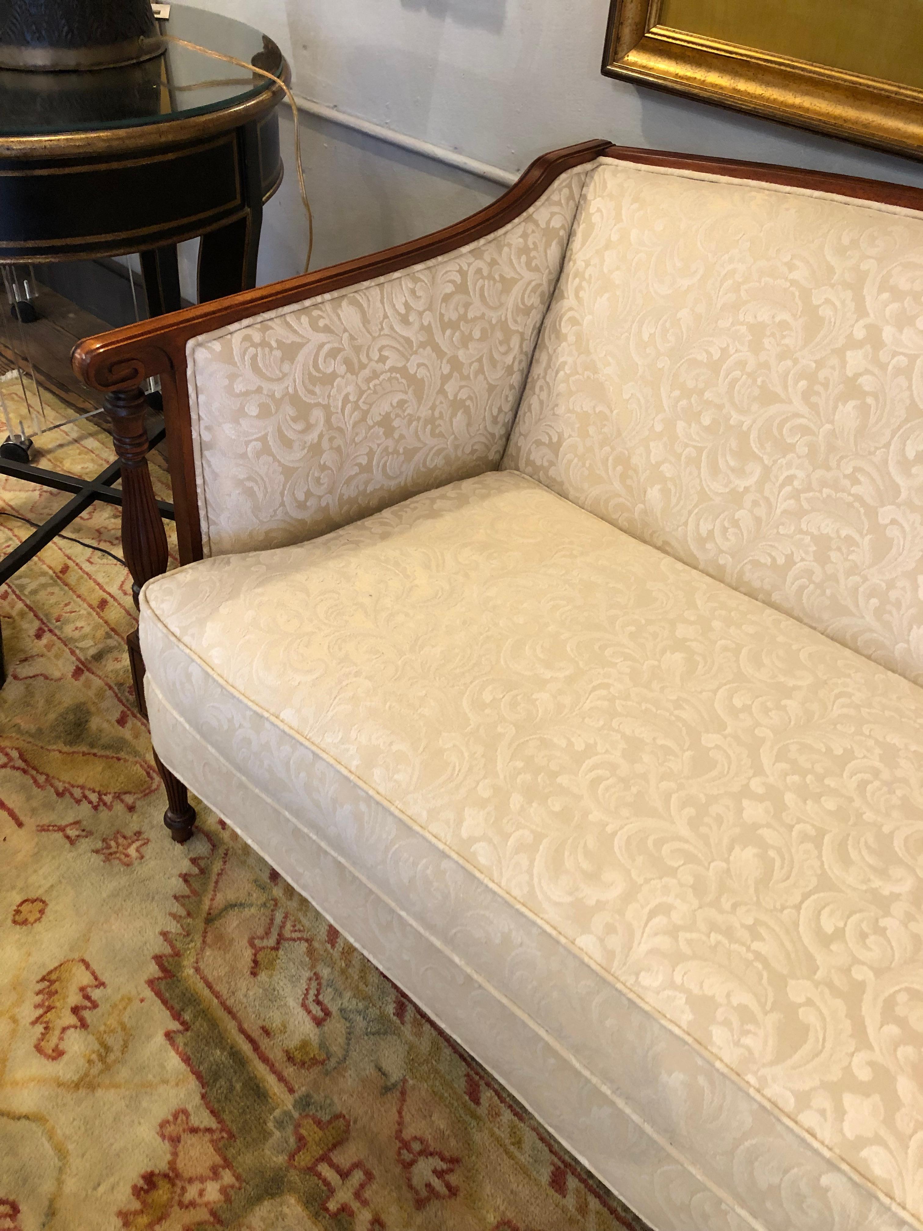 Classically elegant carved mahogany Sheraton style loveseat having sophisticated clean lines, lovely carved arm rests and reeded legs. Upholstery is cream damask. Pretty front and back, finished all the way around.
Measures: arm height 27.5
seat