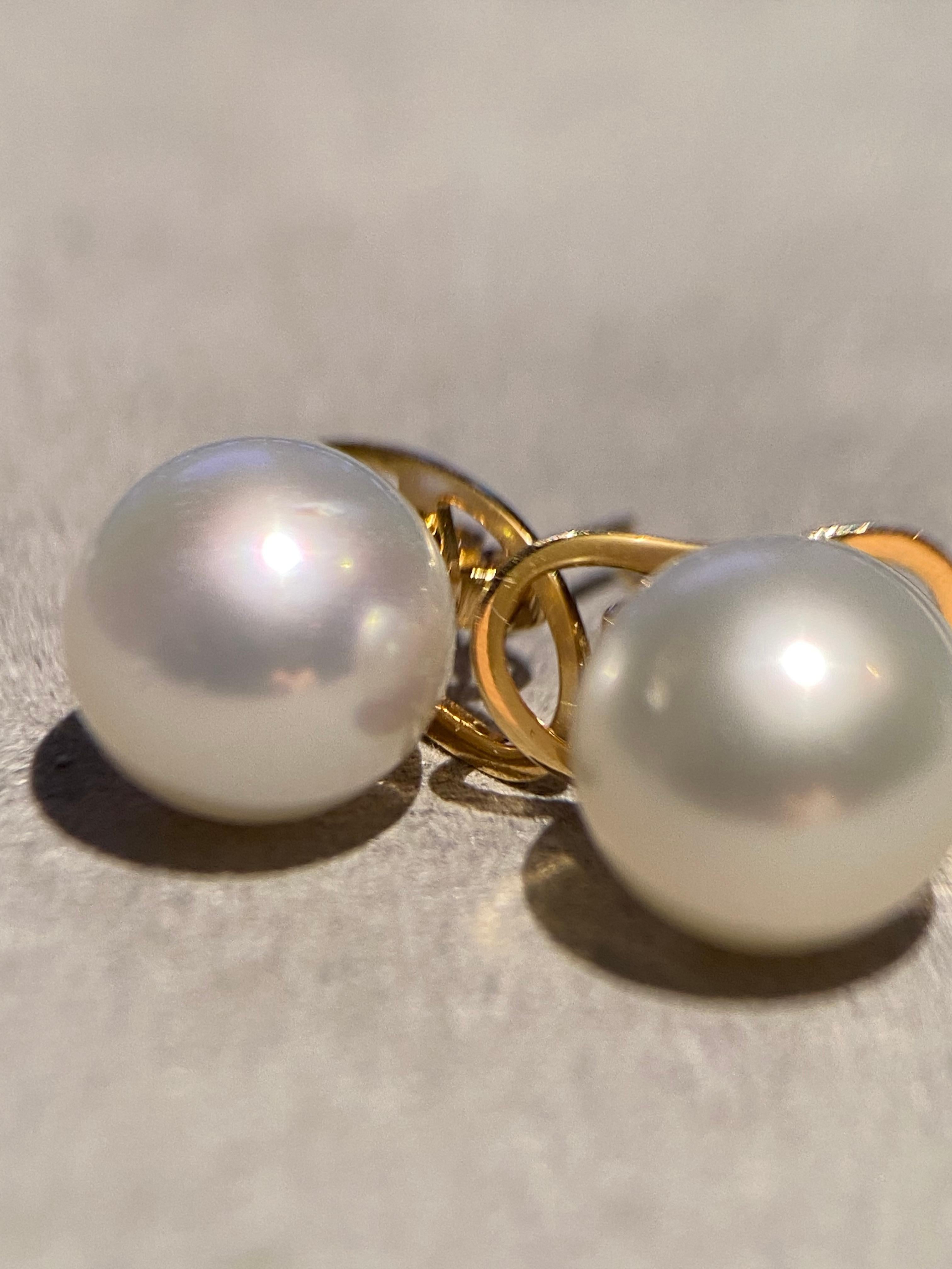 Ein Paar australische Südseeperlen von 9-10 mm. Die Perlen sind rund in der Form mit sehr kleinen Oberflächenfehlern und Unvollkommenheit. Die Perlen sind hochglänzend mit grünem und rosafarbenem Deckstein. Der Ohrstecker ist in 18 Karat Gelbgold