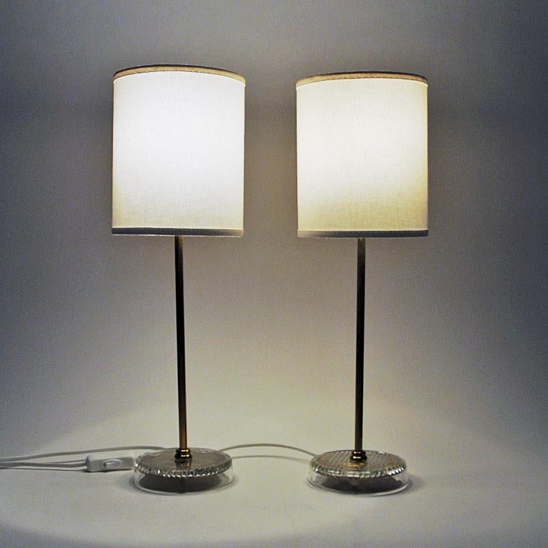 Classic design pair of brass table lamps from EM Eskilstuna - made in the 1960s Sweden. Great as a pair or single lamp in the hallway, livingroom, kitchen etc. The lamps hava a polished brass body standing on a releiffed glass and brass base. Signed