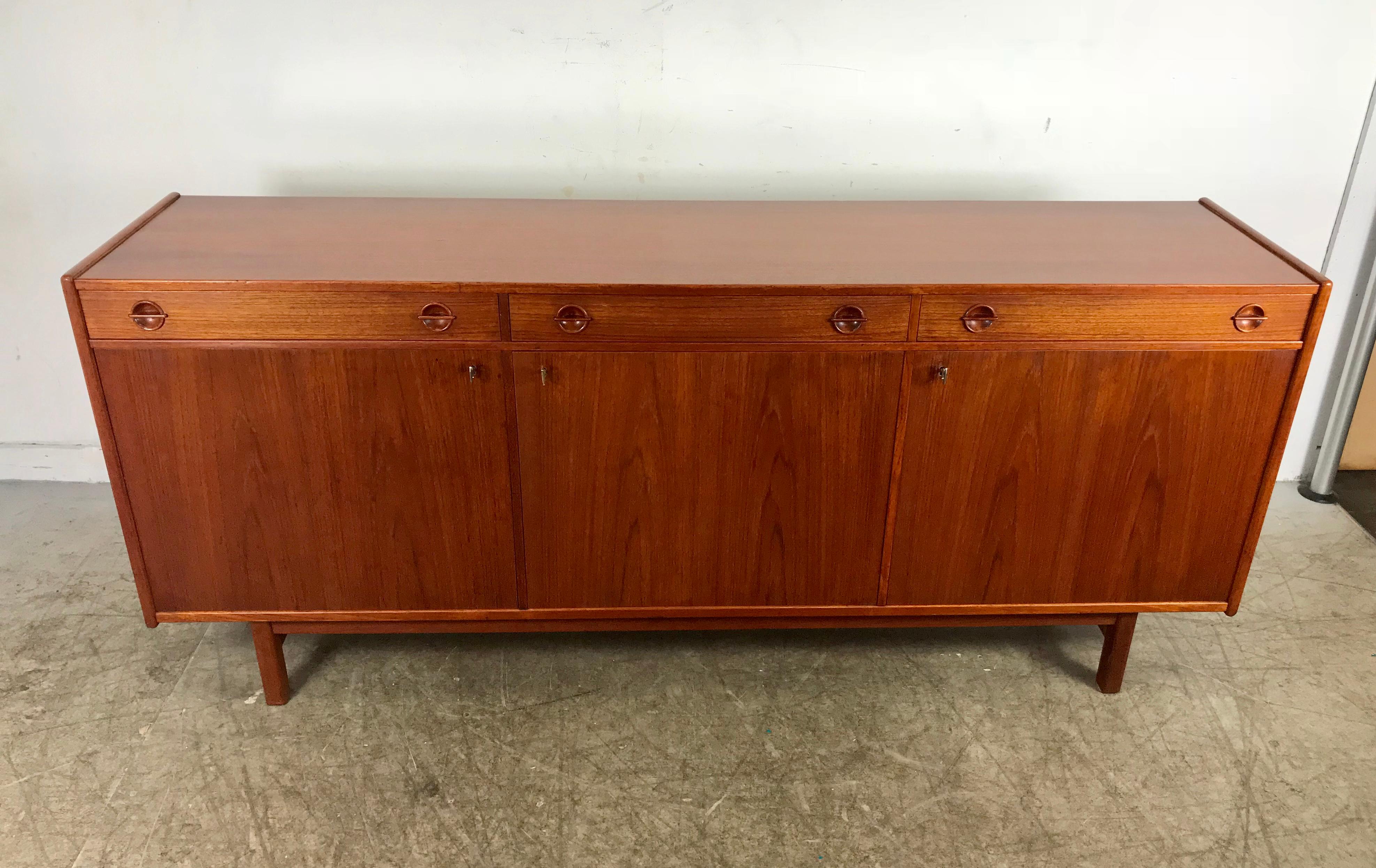 Classic Swedish modern teak credenza by Ulferts Mobler. Amazing quality and construction, stunning book match teak veneers featuring three drawers and three doors right drawer with lined for silverware, sculpted wood design hand pulls, three doors