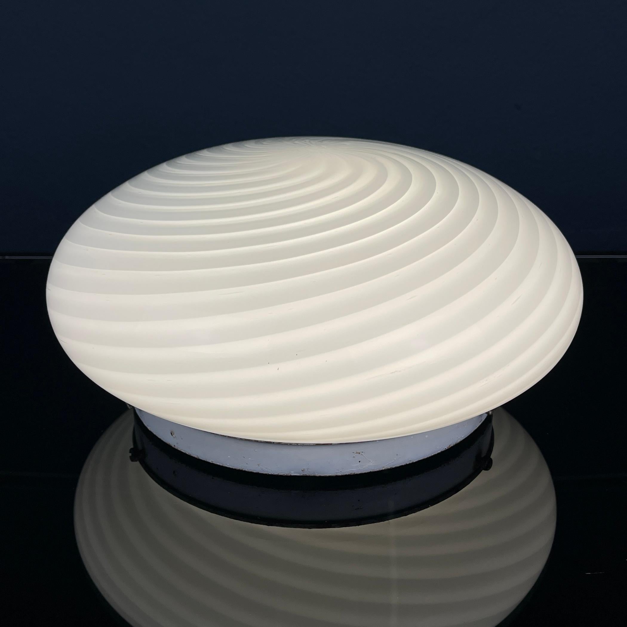 Introduci un tocco di eleganza senza tempo nel tuo spazio con questa lampada classica in vetro di Murano, sapientemente realizzata in Italia negli anni '70. Dal design versatile, questa lampada può essere utilizzata sia come apparecchio da soffitto