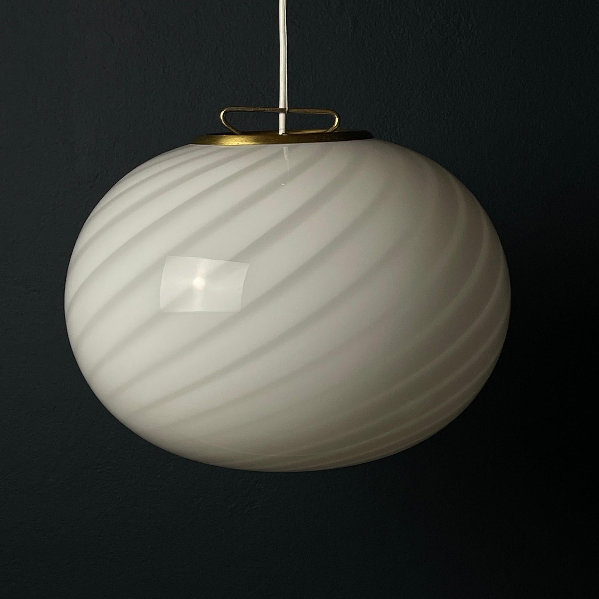Transport your space to the stylish '70s with this captivating Italian swirl Murano lamp. Crafted in Italy, it features exquisite white Murano glass fashioned into a spherical form with elegant bends that exude a sense of timeless beauty. This lamp