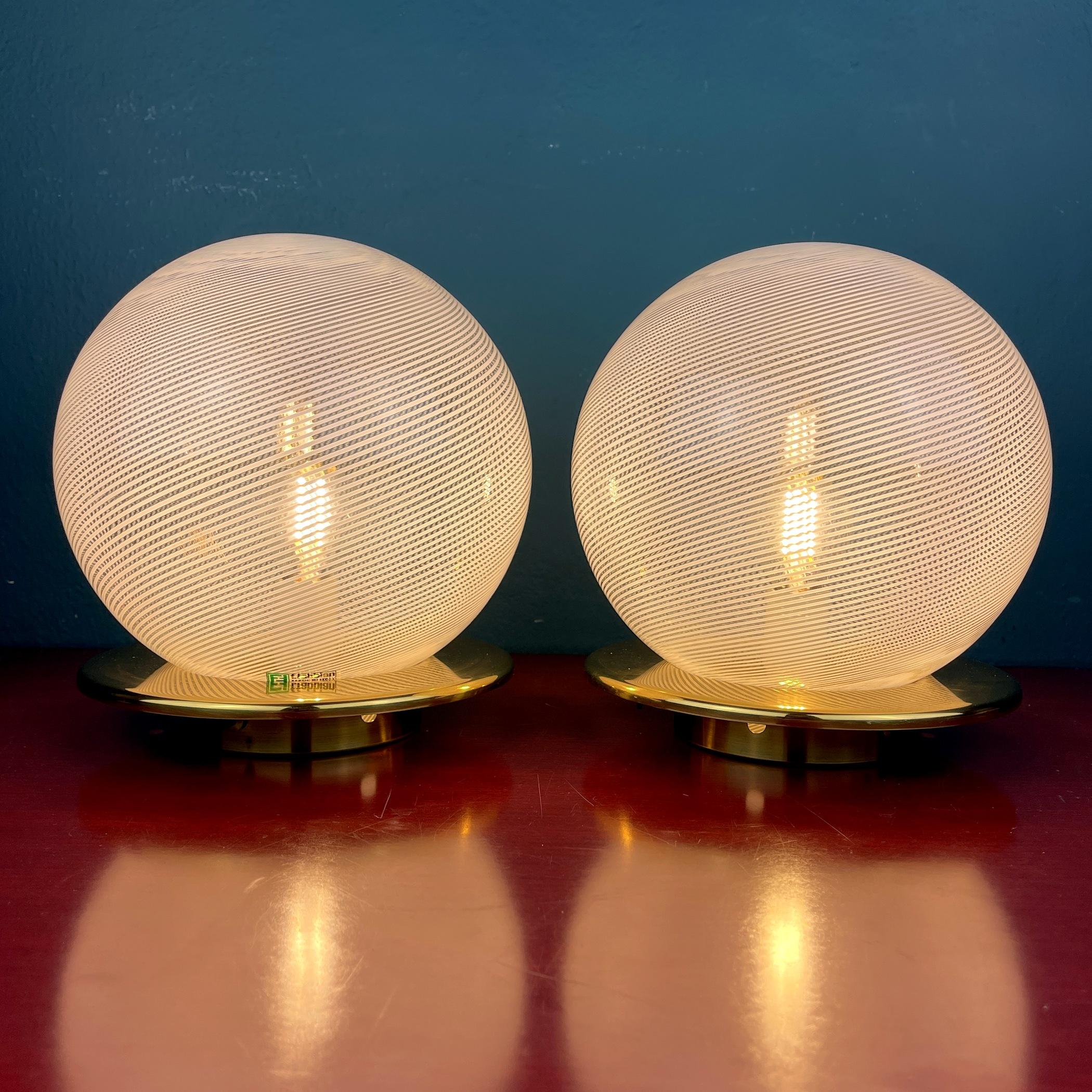 The pair of vintage Murano glass night table lamps were made in Italy in the 1970s. Very beautiful white glass with bends in the form of a sphere. Very good vintage condition. No chips or cracks. The metal has a patina. Requires a standard Edison