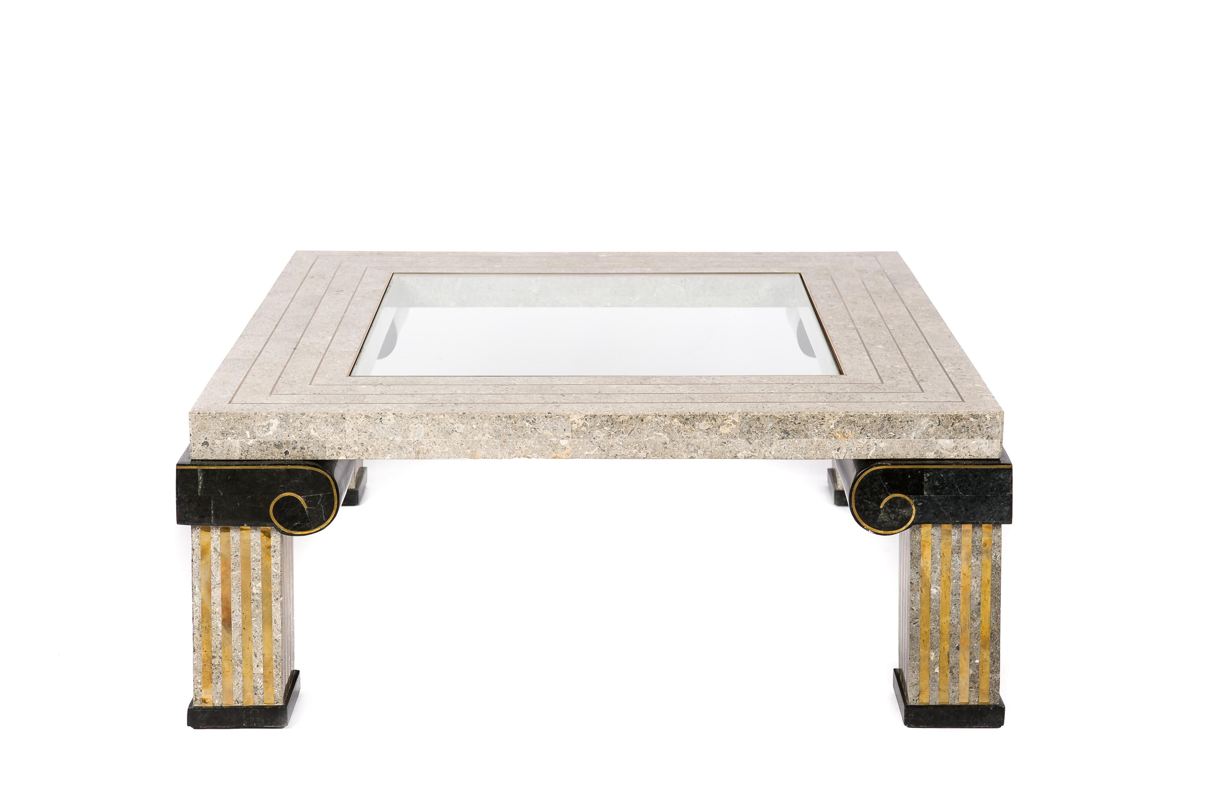 This beautifully handcrafted coffee table with a glass center panel and inlaid brass borders was made by Maitland Smith in the Philipines in the 1980s. It is a rare piece made in the neoclassical style with its ionic fluted pillars ending in a