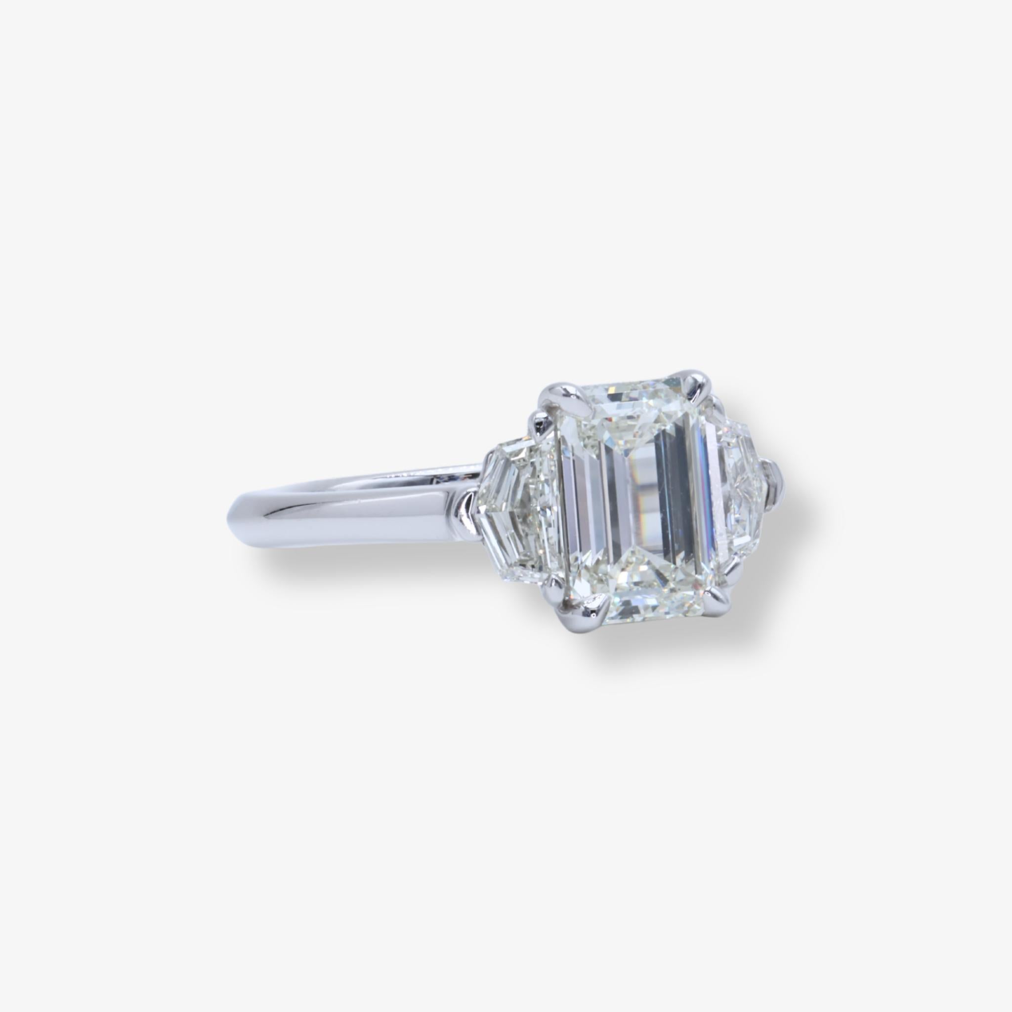 Élégante bague de fiançailles en platine à trois pierres ornée d'un diamant taille émeraude de 1,71 ct certifié GIA J VVS2 flanqué de deux pierres latérales taille Cadillac.

Cette bague de fiançailles à trois pierres et diamant taille émeraude est