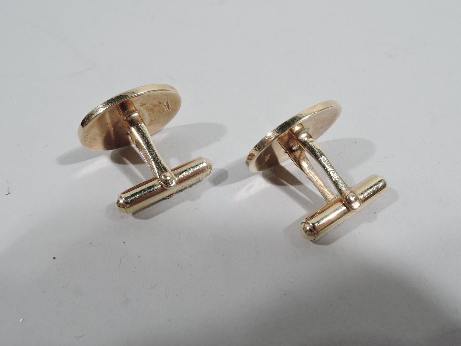 Pair of Classic American 14k gold cufflinks. Engine-turned oval with line border. In leather-bound case with silk lining and fitted velvet. Case top gilt-stamped “Tiffany & Co. / New York”. Cufflinks' marks include “Tiffany & Co.” stamp. Weight