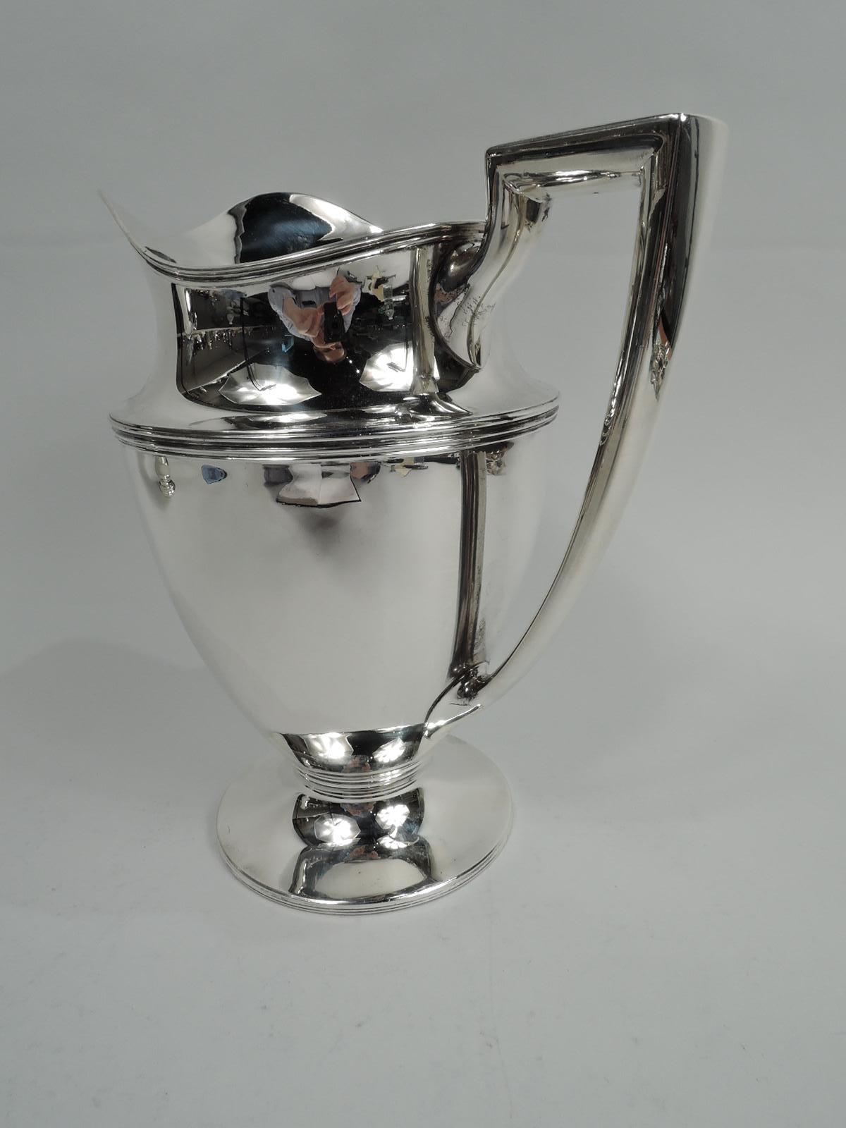 Classic sterling silver water pitcher. Made by Tiffany & Co. in New York, ca 1920. Curved and tapering body, raised foot, scrolled bracket handle, and helmet mouth. Reeding. Fully marked including maker’s stamp, pattern no. 18181, director’s letter