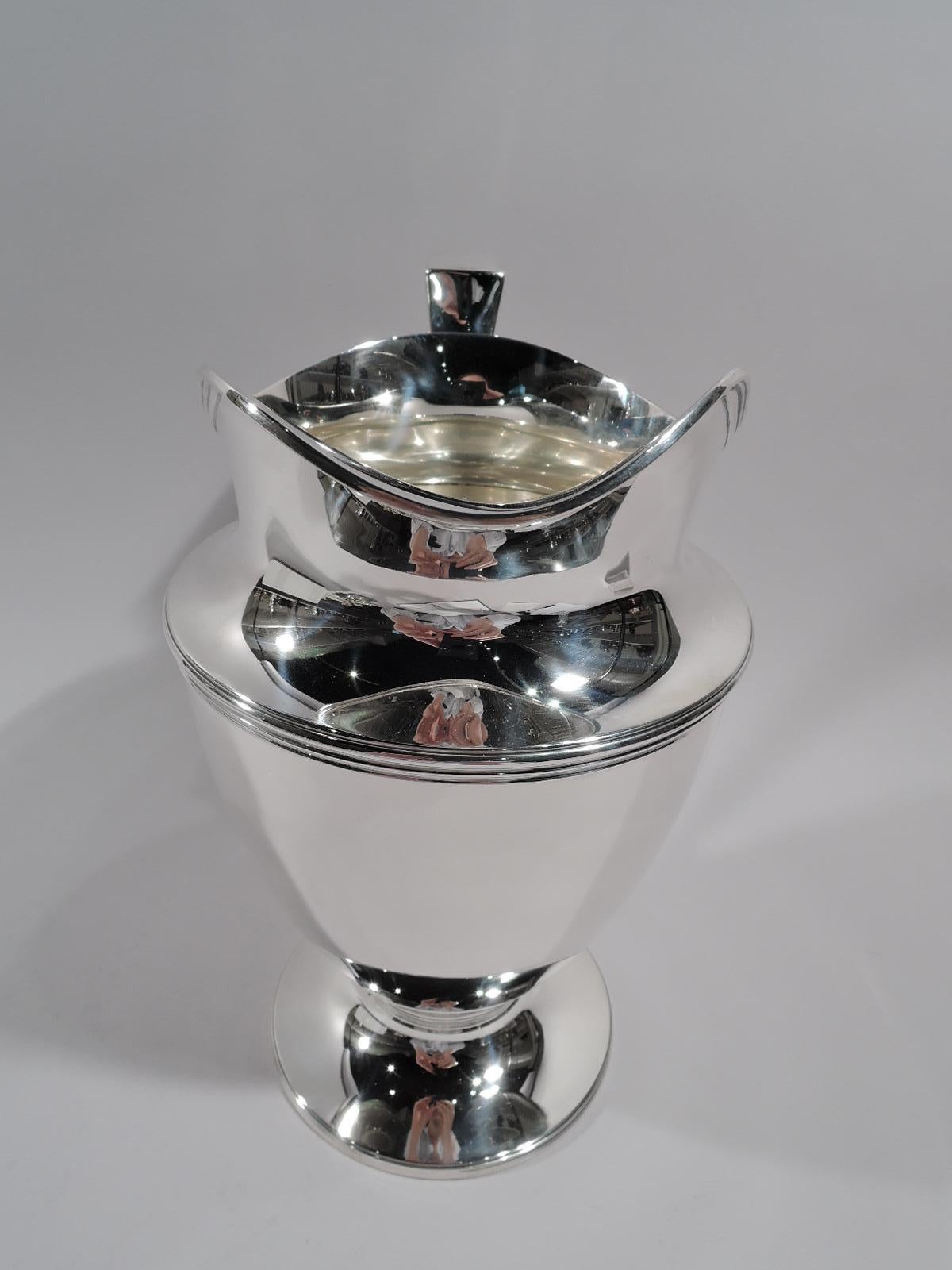 Classic sterling silver water pitcher. Made by Tiffany & Co. in New York, circa 1911. Curved and tapering body, raised and stepped foot, scrolled bracket handle, and helmet mouth. Reeding. Fully marked including pattern no. 18181 (first produced in