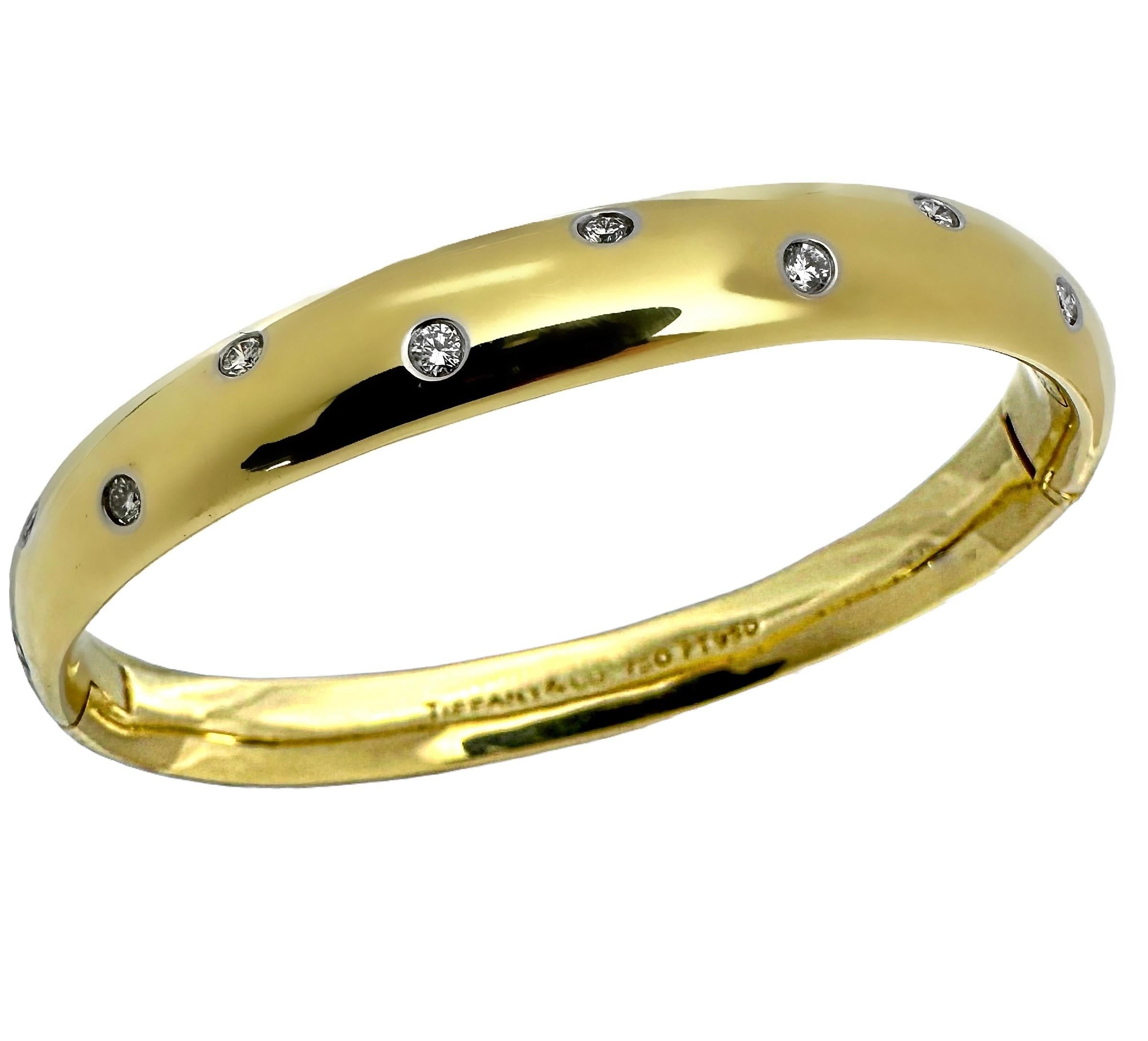 This stunning and instantly recognizable Tiffany & Co. 18K yellow gold and platinum Etoile hinged bangle bracelet is fabricated in the finest manner, befitting the venerated maker. The front is punctuated by ten brilliant cut diamonds, each set in a