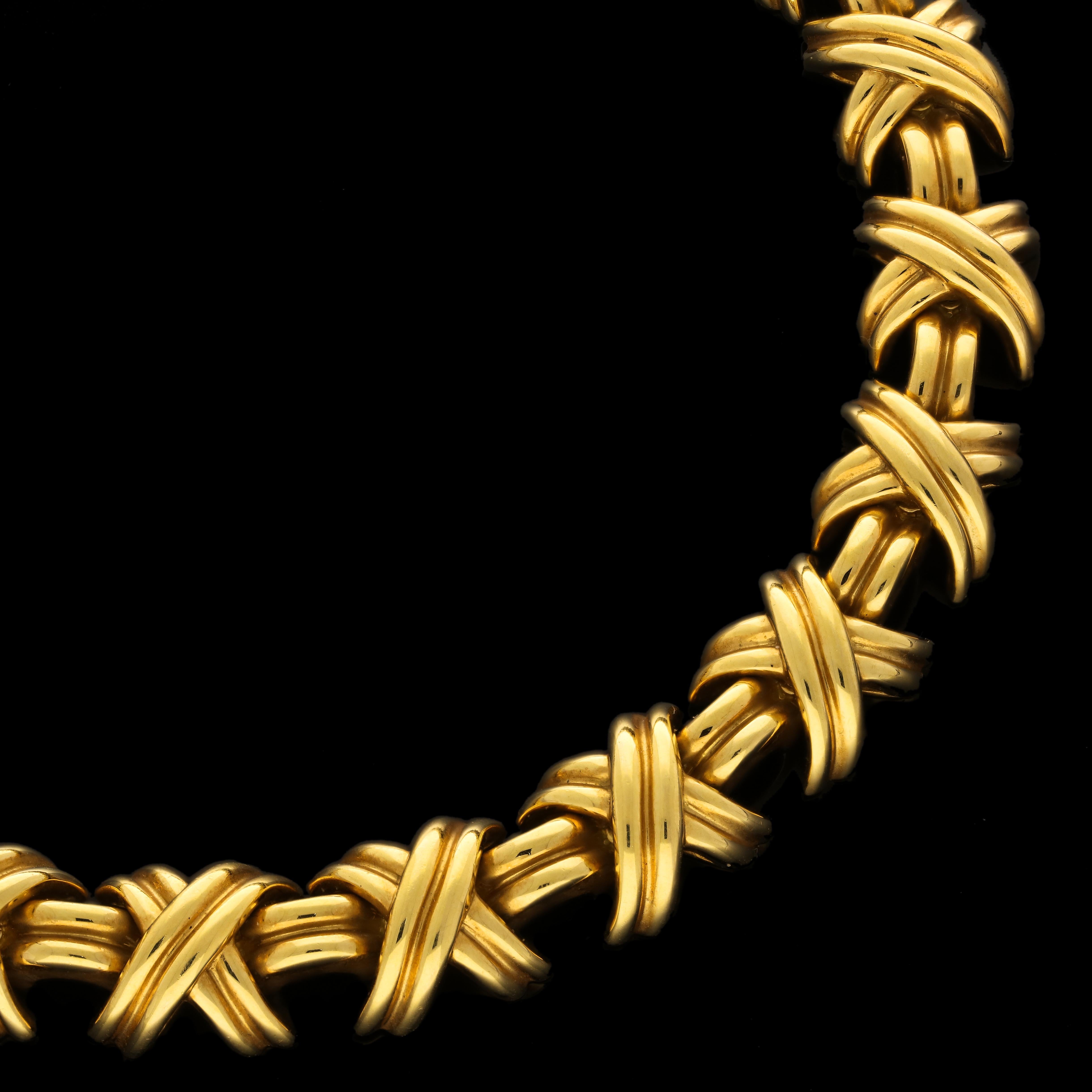 A classic 18ct gold 'Signature' necklace by Tiffany & Co. circa 2000s formed of 31 uniform domed X-shaped motifs in ribbed yellow gold joined by double row arched links, all to a concealed tongue and box clasp. The Tiffany ‘Signature’ collection