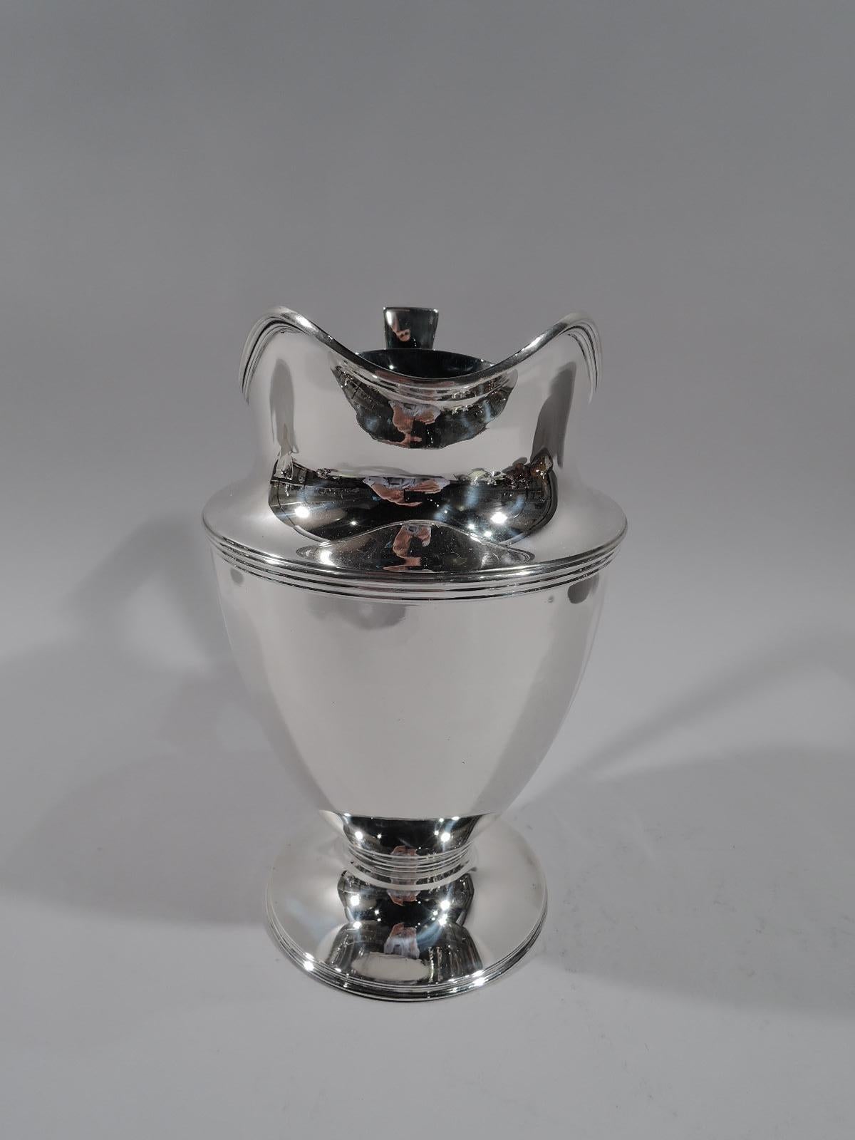 Classic sterling silver water pitcher. Made by Tiffany & Co. in New York, circa 1911. Curved and tapering body, raised and stepped foot, scrolled bracket handle, and helmet mouth. Reeding. Fully marked including pattern no. 18181 (first produced in