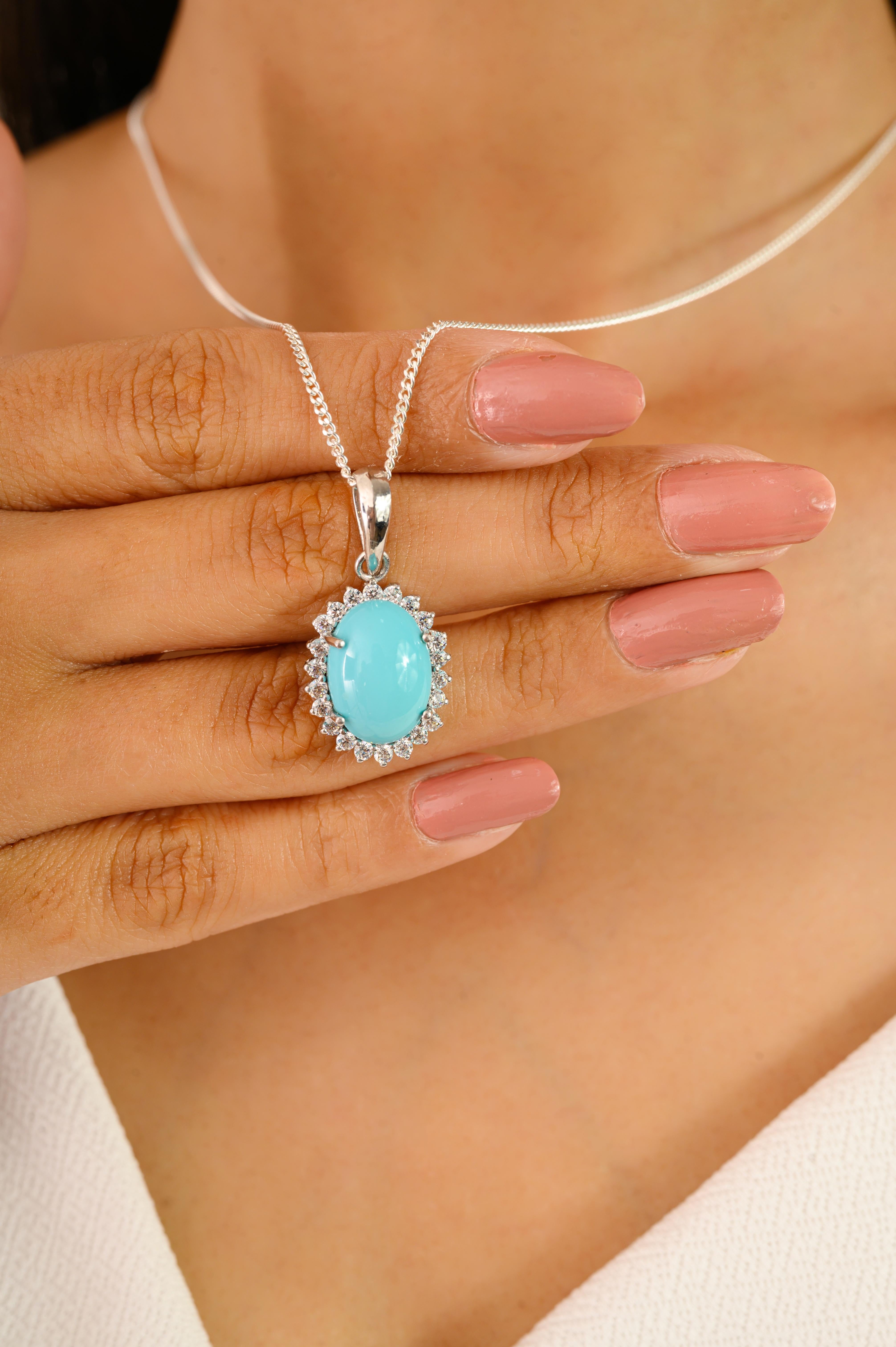 Ce pendentif Turquoise & CZ Cluster Halo Drop est en argent 925. La pierre bleu ciel est entourée d'un halo rayonnant de zircon cubique taillé en diamant, capturant ainsi le charme des modèles anciens avec une touche de modernité. La surface lisse