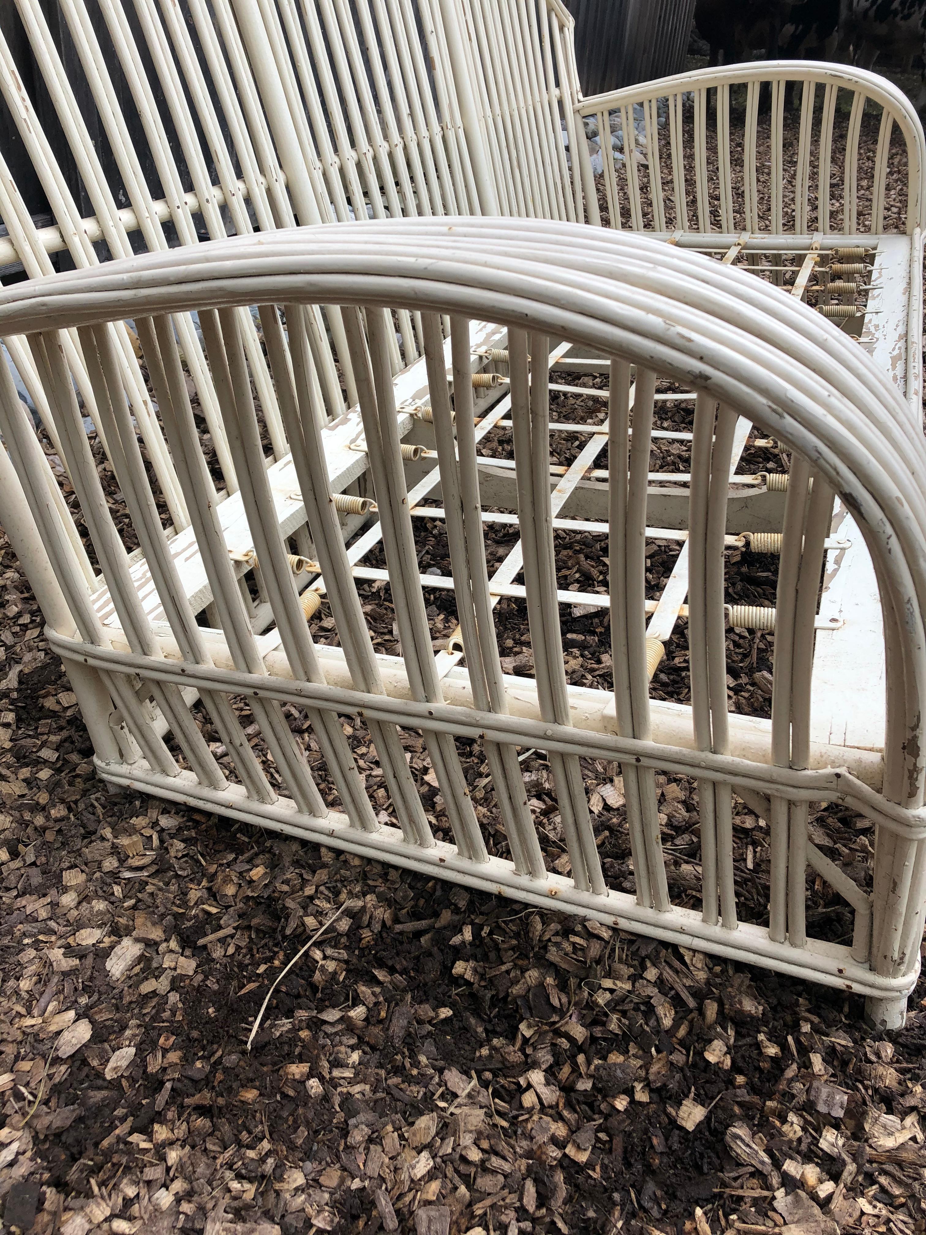 A big classic vintage rattan sofa painted white, having curvy arms and an arc shaped back. Intentionally left in slightly distressed condition. No breaks and very structurally solid. Will need a custom cushion.
Measure: Arm height 22.5.
 