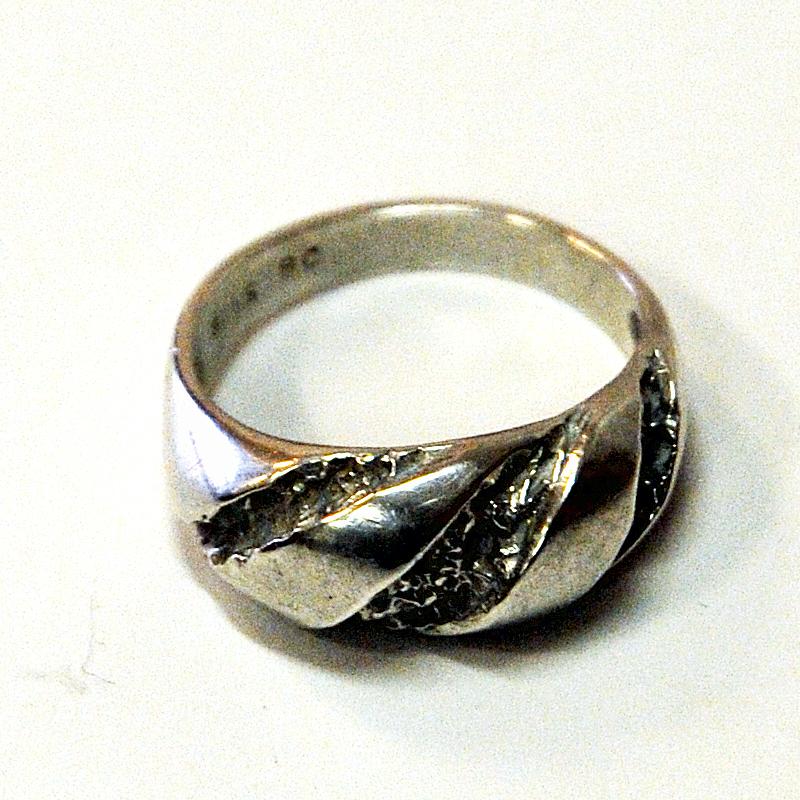 Decorative vintage Scandinavian silvering with a rough cut surface and nice design by Guldateljen AB, Sweden, 1980s.

Stamped: 935S BC. Measures: Inner diameter is 17mm, total height of ring 22 mm. Scandinavian design. Nice and natural patina and